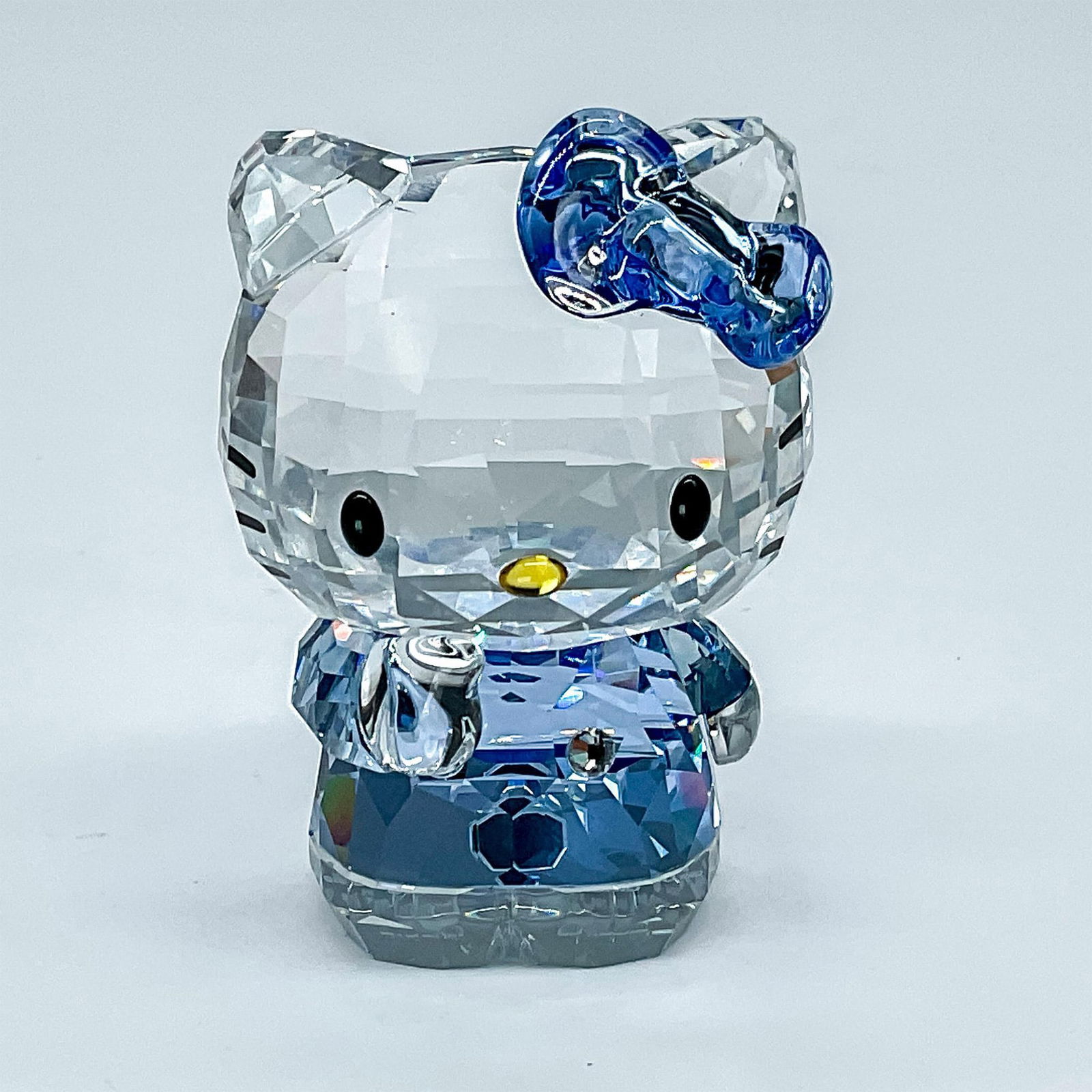 Swarovski Crystal Figurine, Hello Kitty Blue: Hello Kitty is part of the Hello Kitty Sanrio theme group. She is made of clear crystal. Her eyes are made of jet crystal. Hello Kitty is wearing a signature bow in light sapphire crystal. Her dress i