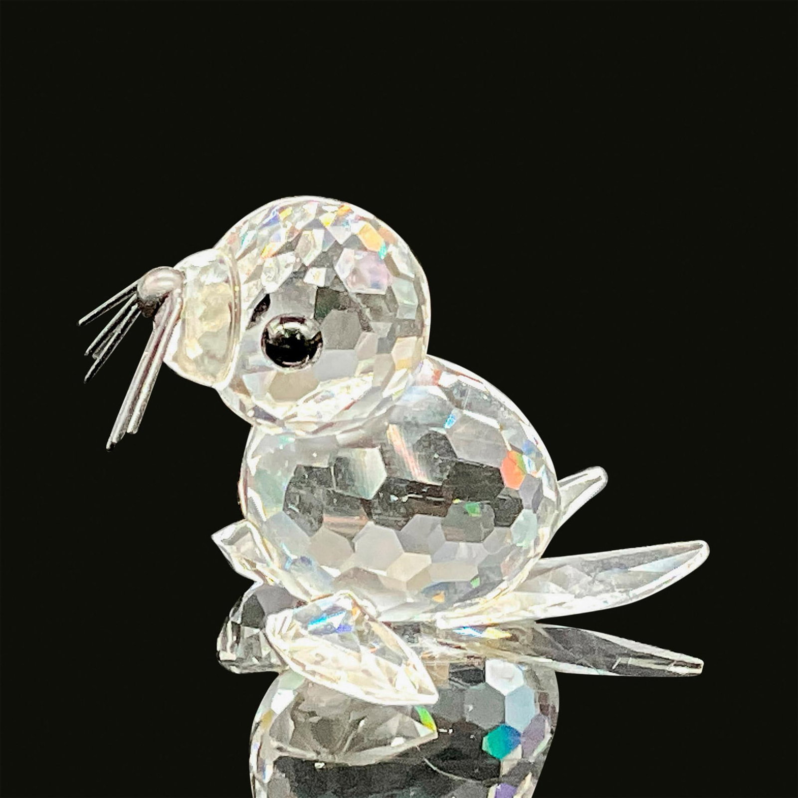 Swarovski Crystal Figurine, Mini Seal 012530: A clear crystal figure of a baby seal on all four flippers with black crystal eyes and black metal whiskers. Swarovski backstamp. This item has its original box. Dimensions of the original box: 2.5"H 