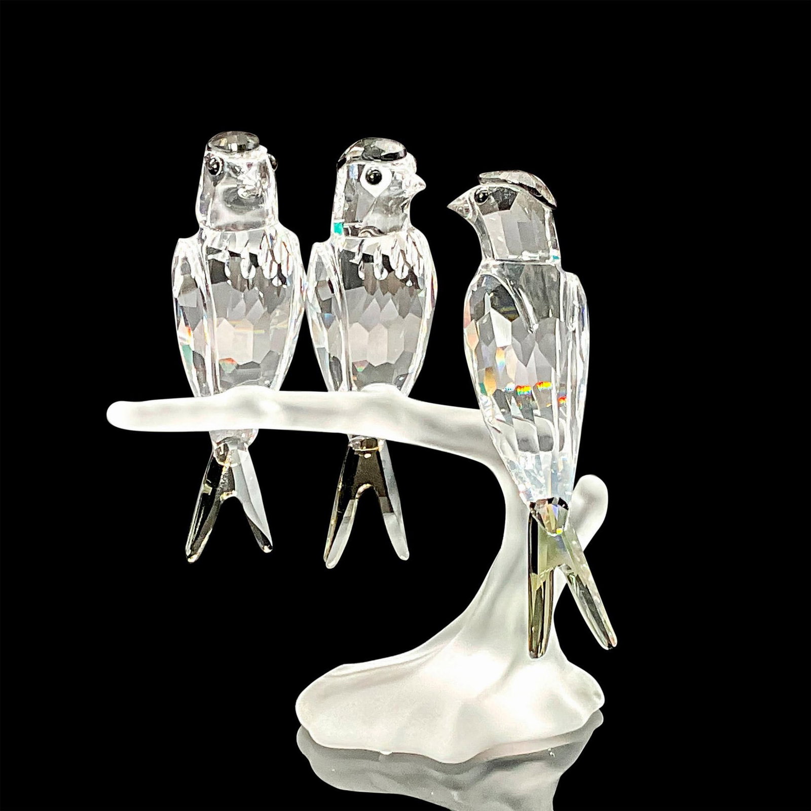 Swarovski Crystal Figurine, Swallows Artist Signed: Three clear faceted crystal birds with black diamond stain crystal head and tail feathers. Perched on a frosted branch. Swarovski acid mark. This item has its original box which measures 6"L x 6"W x 3