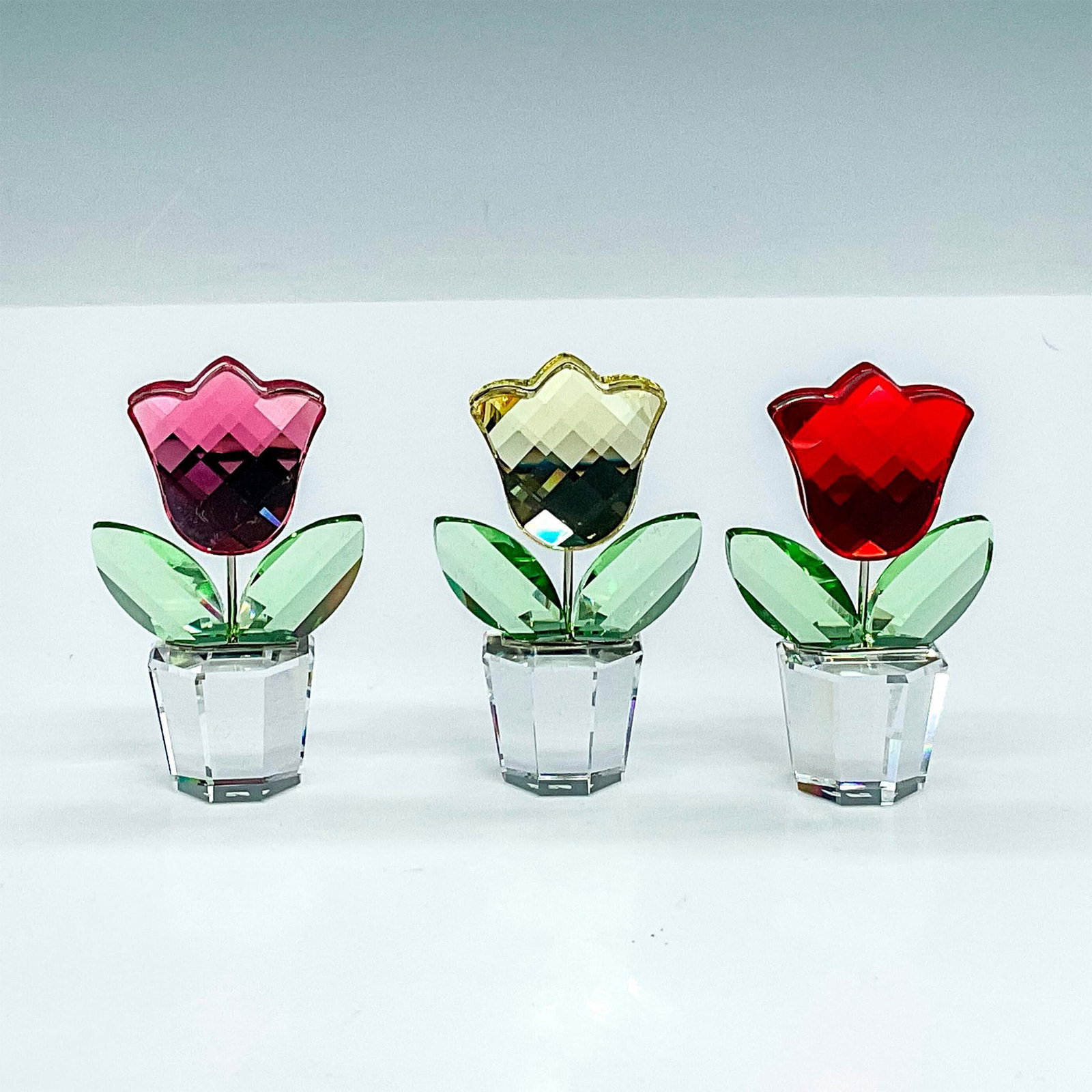 3pc Swarovski Crystal Flowers, Colored Tulips in Pots: Adorable tulips in yellow, red, and pink, all-in clear pots. Swarovski etched backstamp. Pot of clear faceted crystal. This item has its original box which measures 3"L x 3"W x 1.5"H. Dimensions: 1"L 