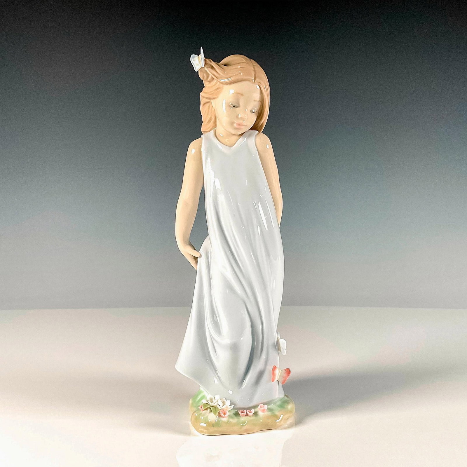 Friend of The Butterflies 1006963 - Lladro Porcelain Figurine: Glossy finish figure modeled as a young girl in blue dress with butterflies resting on her. Lladro backstamp. Artist: Alfredo Llorens Issued: 2003 Dimensions: 3.25"L x 3"W x 8.5"H Manufacturer: Lladro