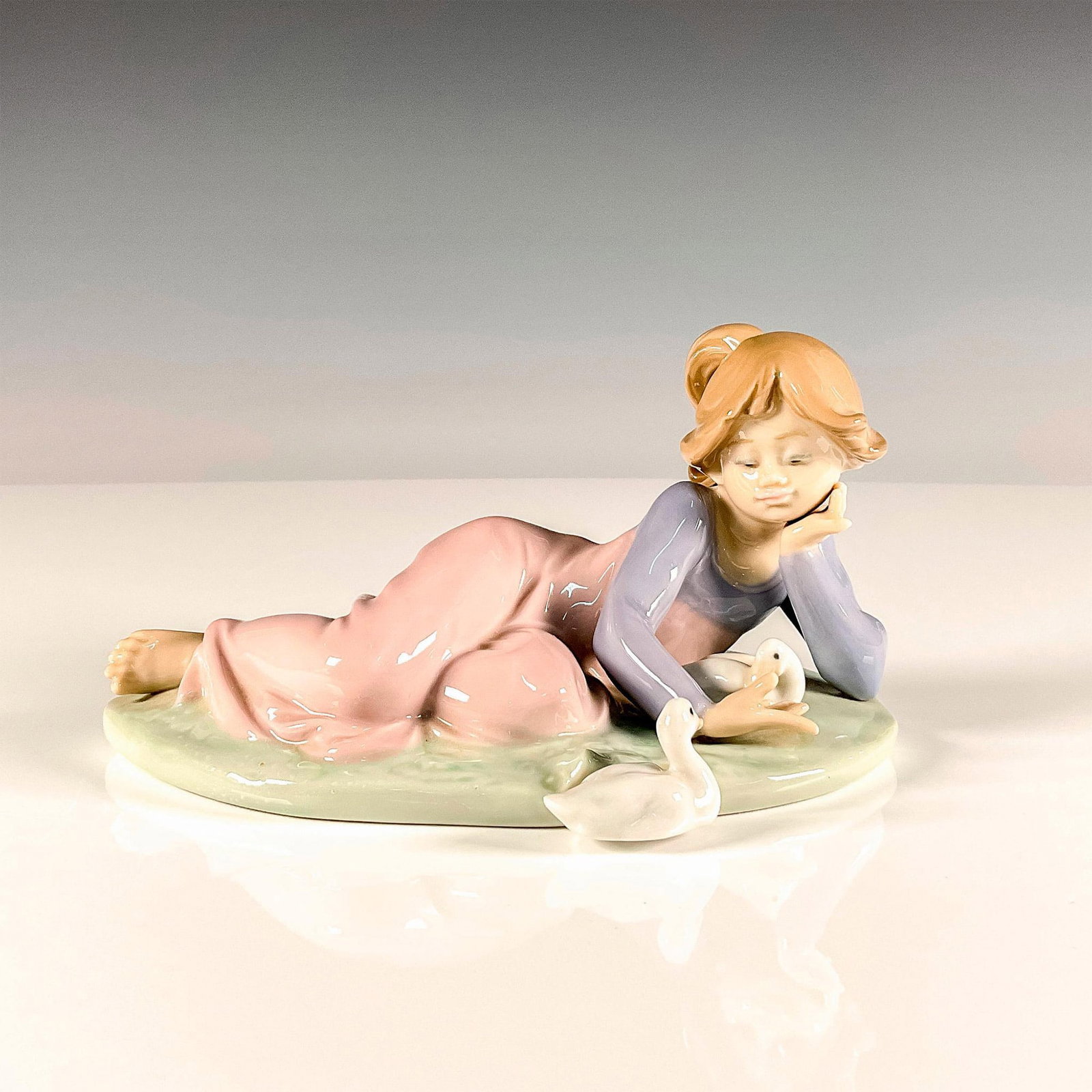 Playful Friends 1005609 - Lladro Porcelain Figurine: Glossy finish modeled as a young girl playing with two ducks. Lladro backstamp. Artist: Antonio Ramos Issued: 1989-1995 Dimensions: 6.5"L x 4.5"W x 3.5"H Manufacturer: Lladro Country of Origin: S
