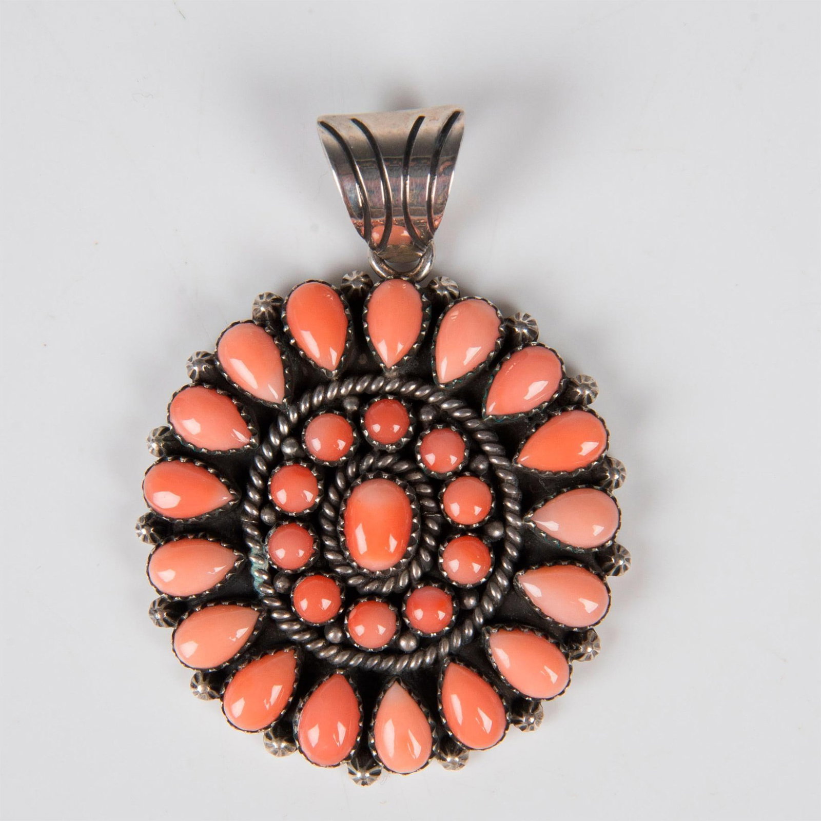 Mary Marie Sterling Silver and Coral Pendant: This beautiful pendant is created by a member of one of the most celebrated Navajo jewelry making families. Set in sterling silver the cluster of pastel coral teardrop and round cabochon stones is cla