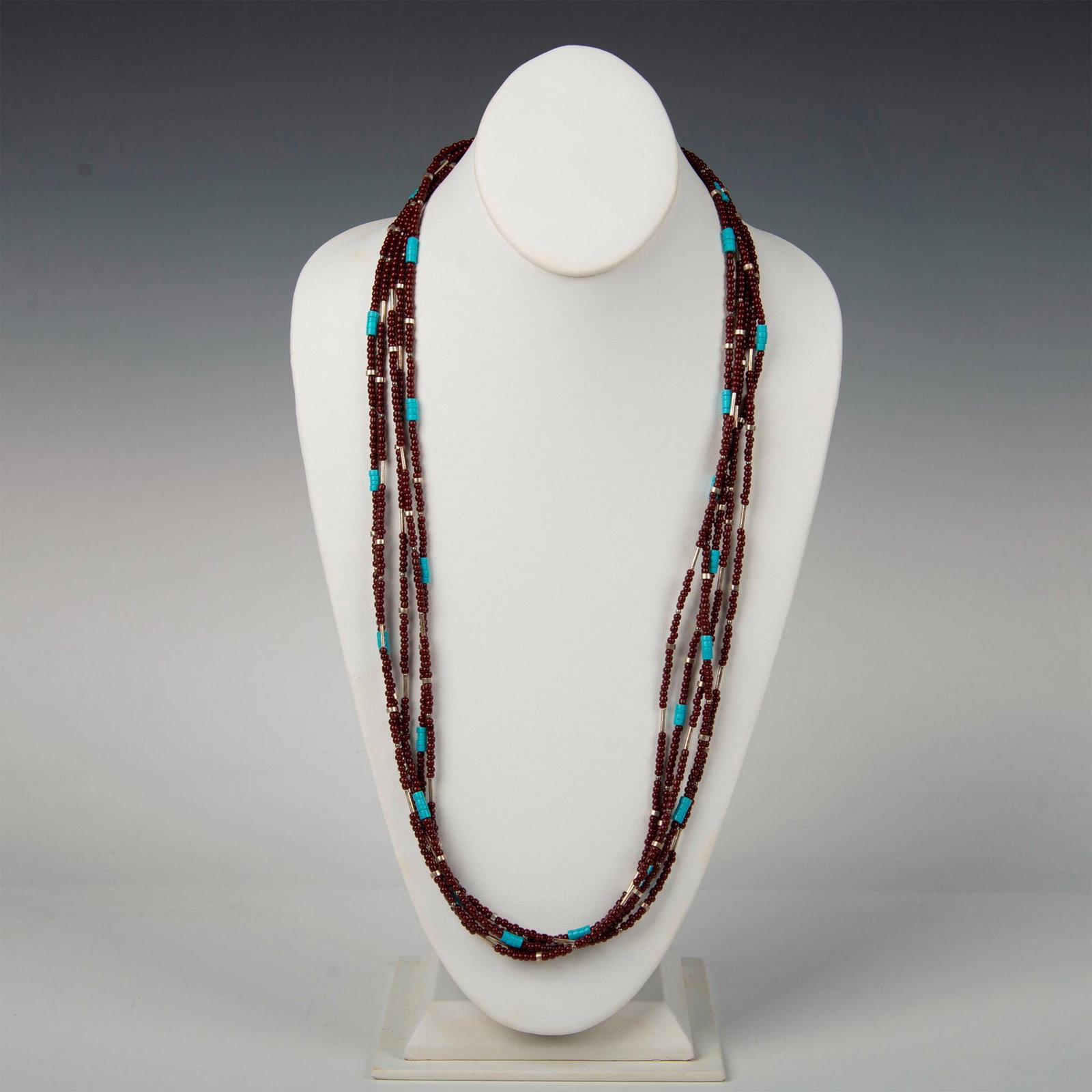 Native American Sterling Silver and Beaded Necklace: Hand made five strands of maroon, turquoise, and silver beads with Sterling silver tips and hook clasp. Marked Sterling. Dimensions: 30.5"L Country of Origin: United States