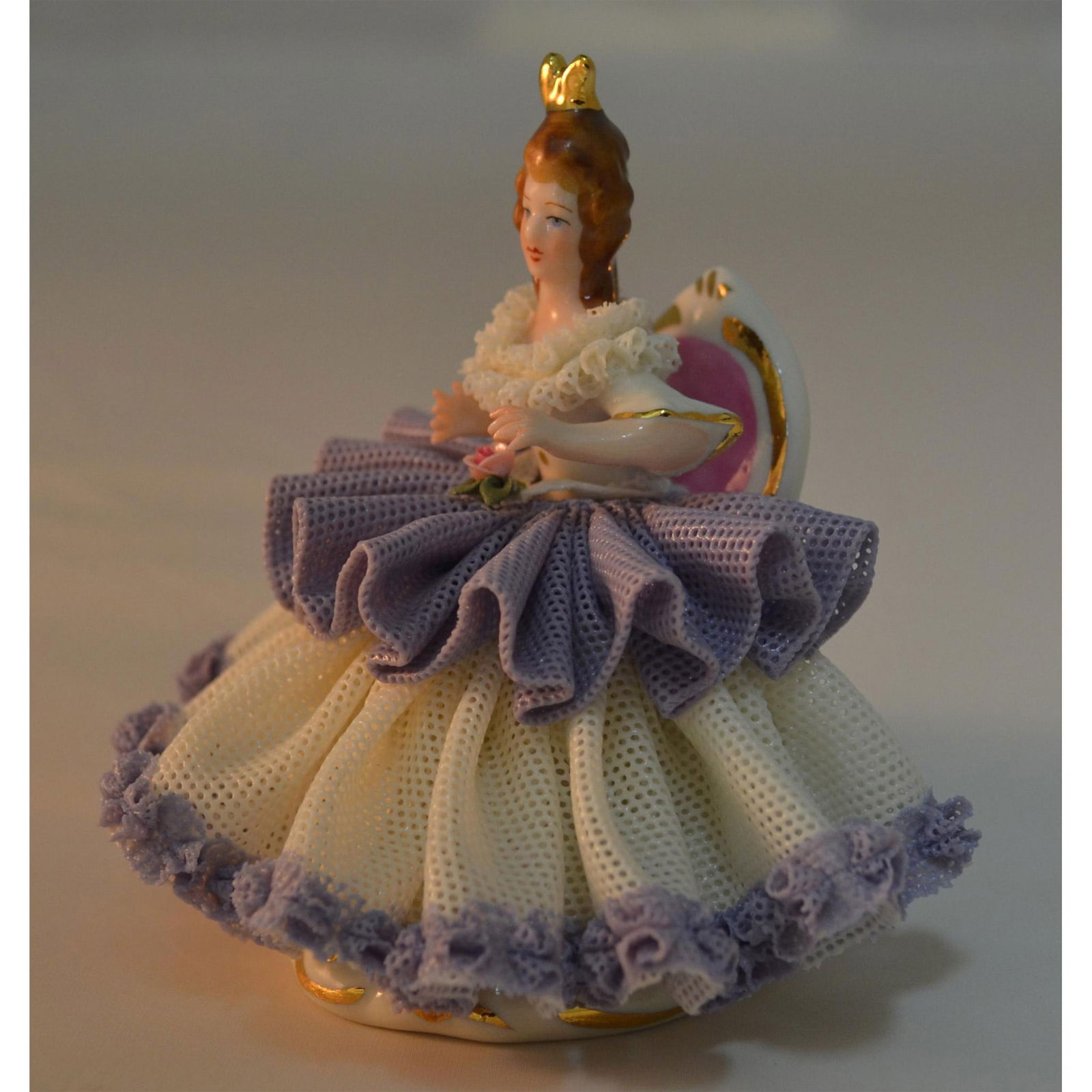 Dresden Porcelain Lady In Lace Seated: Glazed Porcelain Decorated, hand created, hand painted in fine detail by the Artists of Dresden. Featuring a Lady seated, dressed elegantly in a Purple and White Lace Porcelain Dress, with Gold Crown.