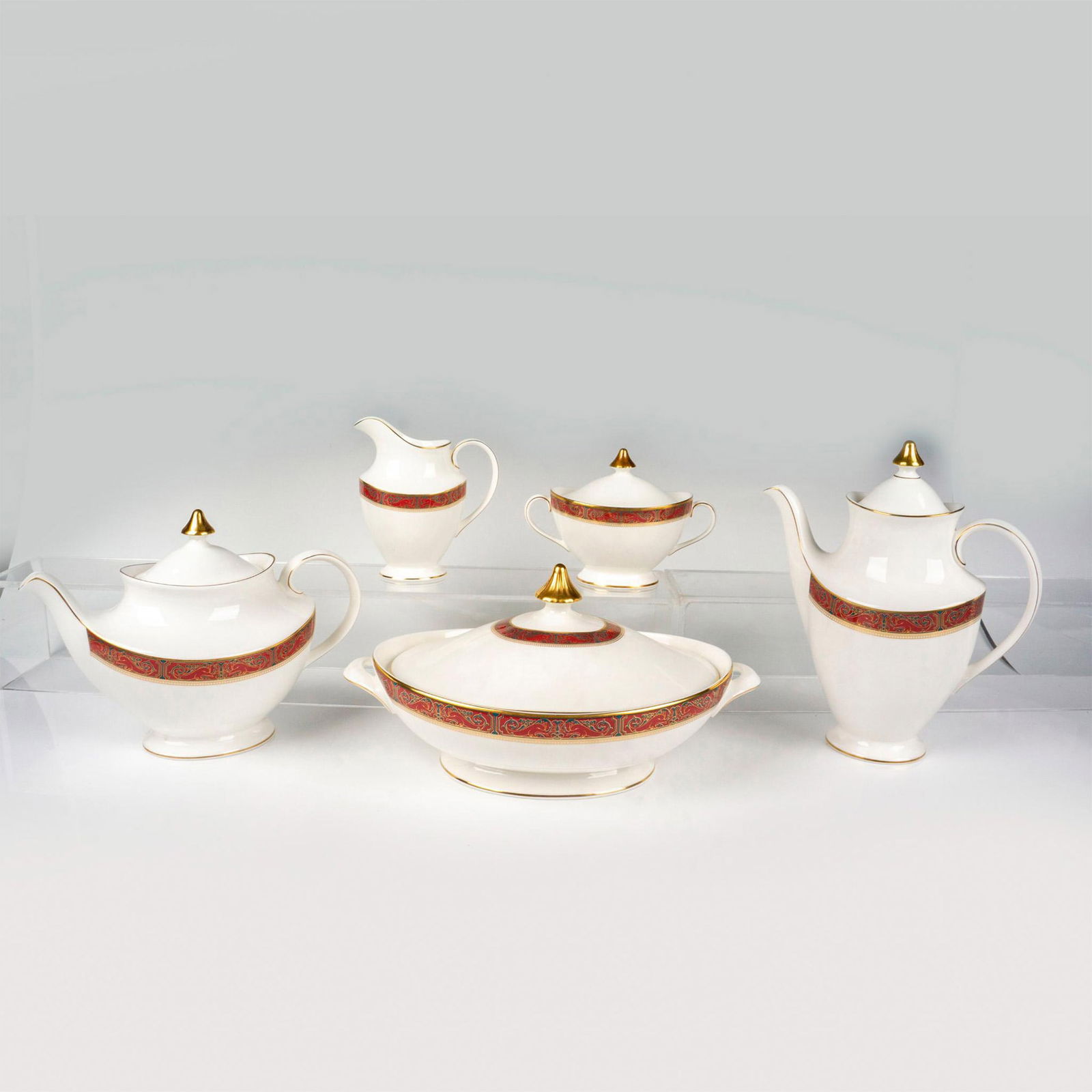 5pc Royal Doulton Bone China Serveware, Martinique: Five tableware serving items in white with a blue floral and scroll gold design on maroon. Royal Doulton backstamp. Teapot 10.5"L x 5.25"W x 7.5"H. Coffee pot 9"L x 4.25"W x 10"H. Lidded sugar bowl 6.