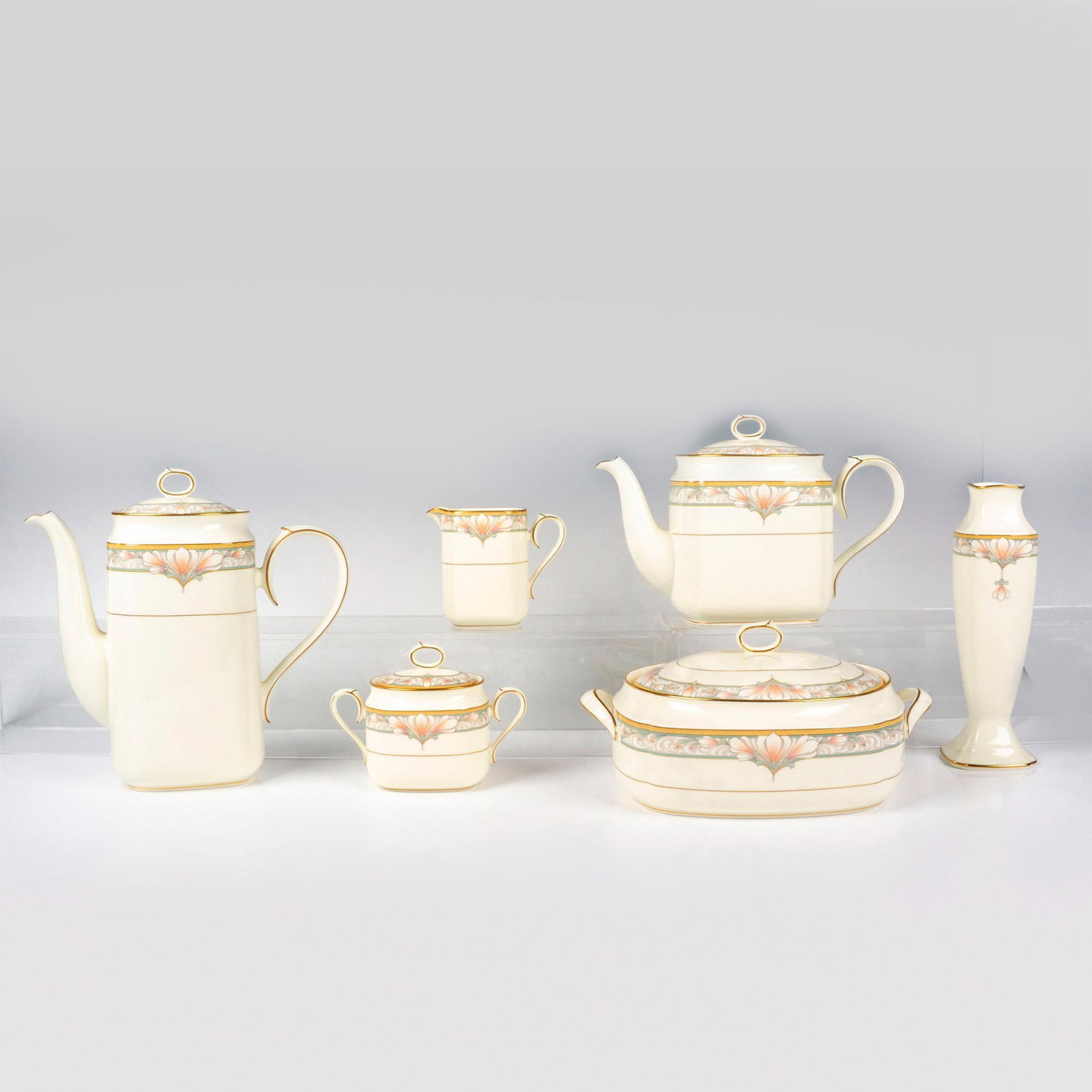 6pc Noritake Bone China Tea Service Serveware, Barrymore: Six tableware serving items in cream color with pink and blue floral design with gold rims and accents. Noritake backstamp. Teapot 10.5"L x 4.25"W x 7"H. Coffee pot 9.75"L x 3.5"W x 9.5"H. Vase 2.75"L