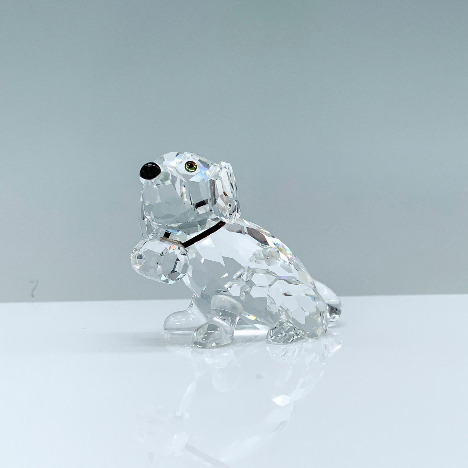 Swarovski Crystal Figurine, Saint Bernard Puppy: A clear crystal figurine of a Saint Bernard pup wearing a rescue barrel around his neck with melon-colored crystal eyes and a black crystal snout. Swarovski backstamp. This item has its original box. 