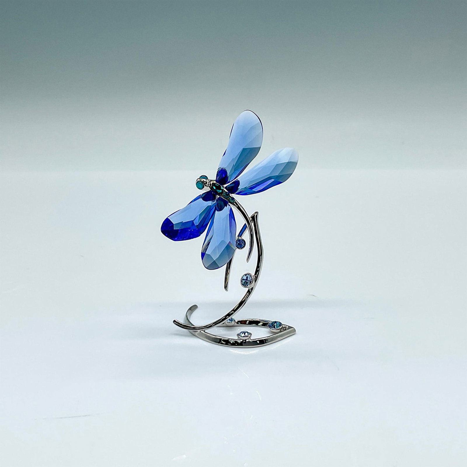 Swarovski Crystal Society Figurine, Dragonfly: Exclusive event piece for SCS members. Blue crystal winged dragonfly on a silver-tone metal base. Swarovski marked. This item has its original box: 3.25"W x 4.75"H. Artist: Elisabeth Adamer Issued: 20
