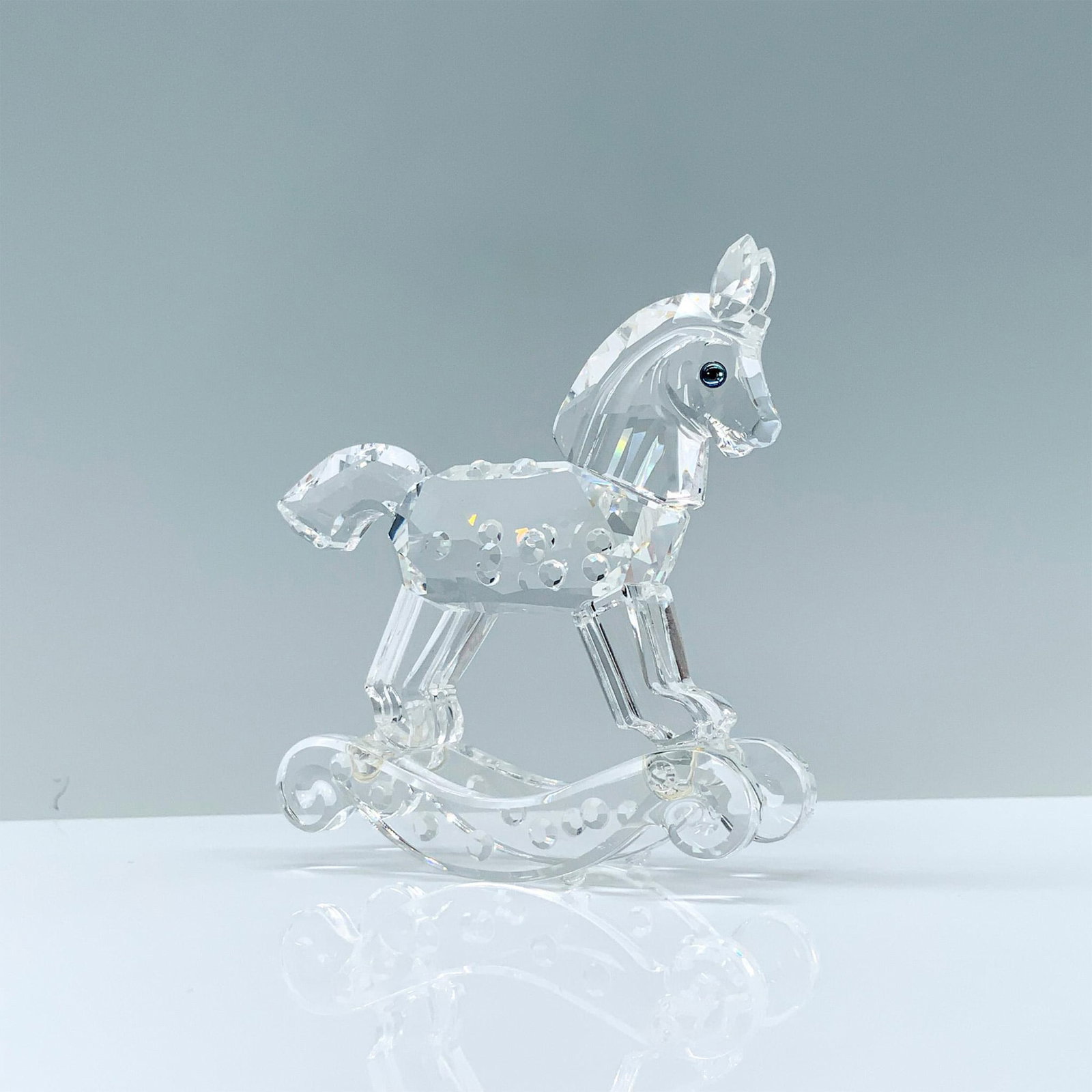 Swarovski Crystal Figurine, Rocking Horse: A clear crystal figurine of a toy rocking horse that has raised crystal points and cerulean-colored eyes. Swarovski backstamp. This item has its original box. Dimensions of the original box: 3.75"H x 