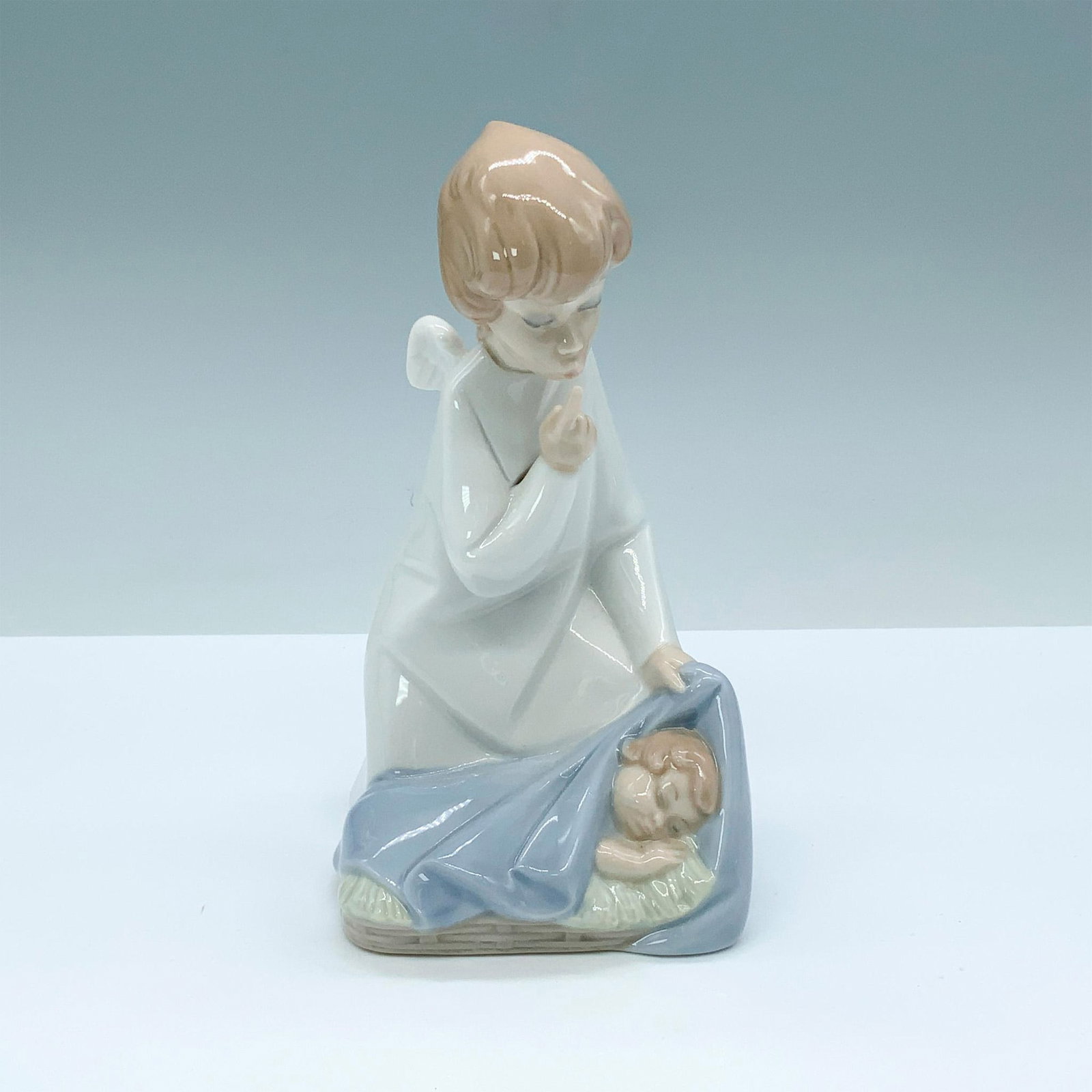 Angel With Child 1004635 - Lladro Porcelain Figurine: Glossy finish; Lladro backstamp. Artist: Juan Huerta Issued: 1969 - 2002 Dimensions: 7"H x 3.5"W Manufacturer: Lladro Country of Origin: Spain