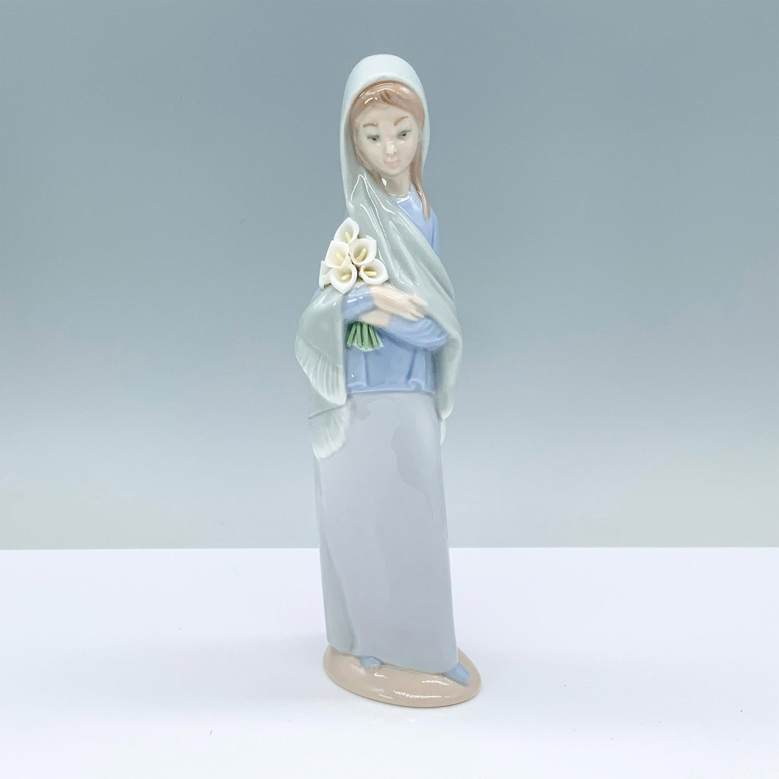 Girl With Calla Lilies 1004650 - Lladro Porcelain Figurine: Glossy finish; Lladro backstamp. Artist signature. Box measures: 5.75"L x 5"W x 11"H. Artist: Vicente Martinez Issued: 1969 - 1998 Dimensions: 9"H x 2.75"W Manufacturer: Lladro Country of Origin:<