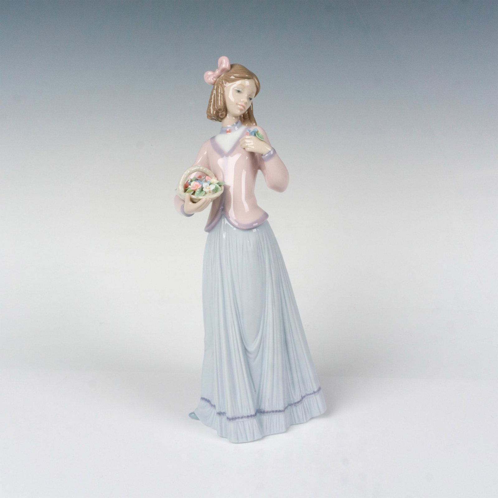 Innocence In Bloom 1007644 - Lladro Porcelain Figurine: Glossy finish; Lladro backstamp. Box measures: 12"L x 7"W x 5.5"H. Artist: Jose Puche Issued: 1996 - 1996 Dimensions: 9.75"H x 4.25"W Manufacturer: Lladro Country of Origin: Spain