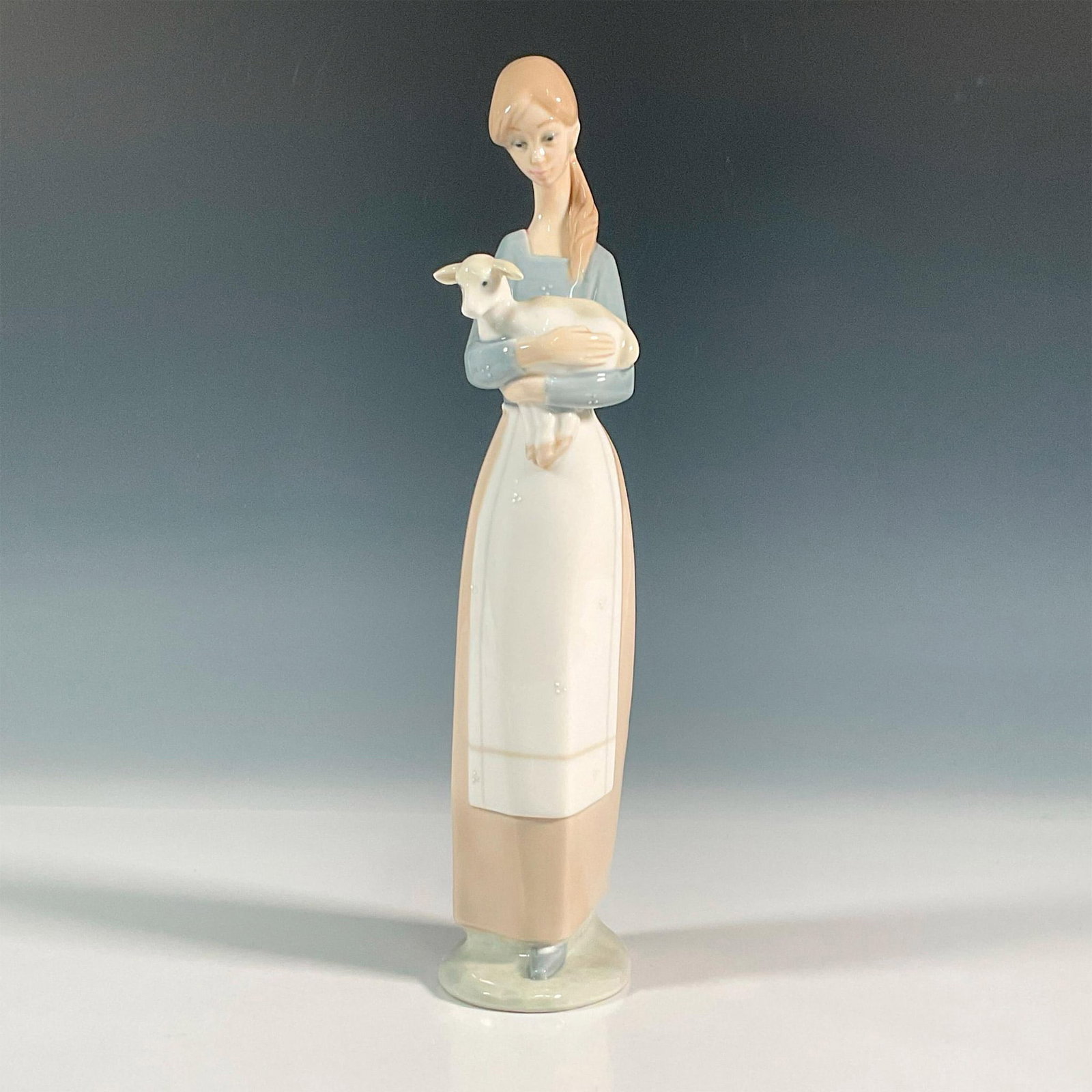 Girl With Lamb 1004505 - Lladro Porcelain Figurine: Glossy finish figure of a girl holding an adorable lamb in her arms. Lladro backstamp. Artist: Fulgencio Garcia Issued: 1969-2001 Dimensions: 2.25"L x 3.5"W x 10.5"H Manufacturer: Lladro Country of O