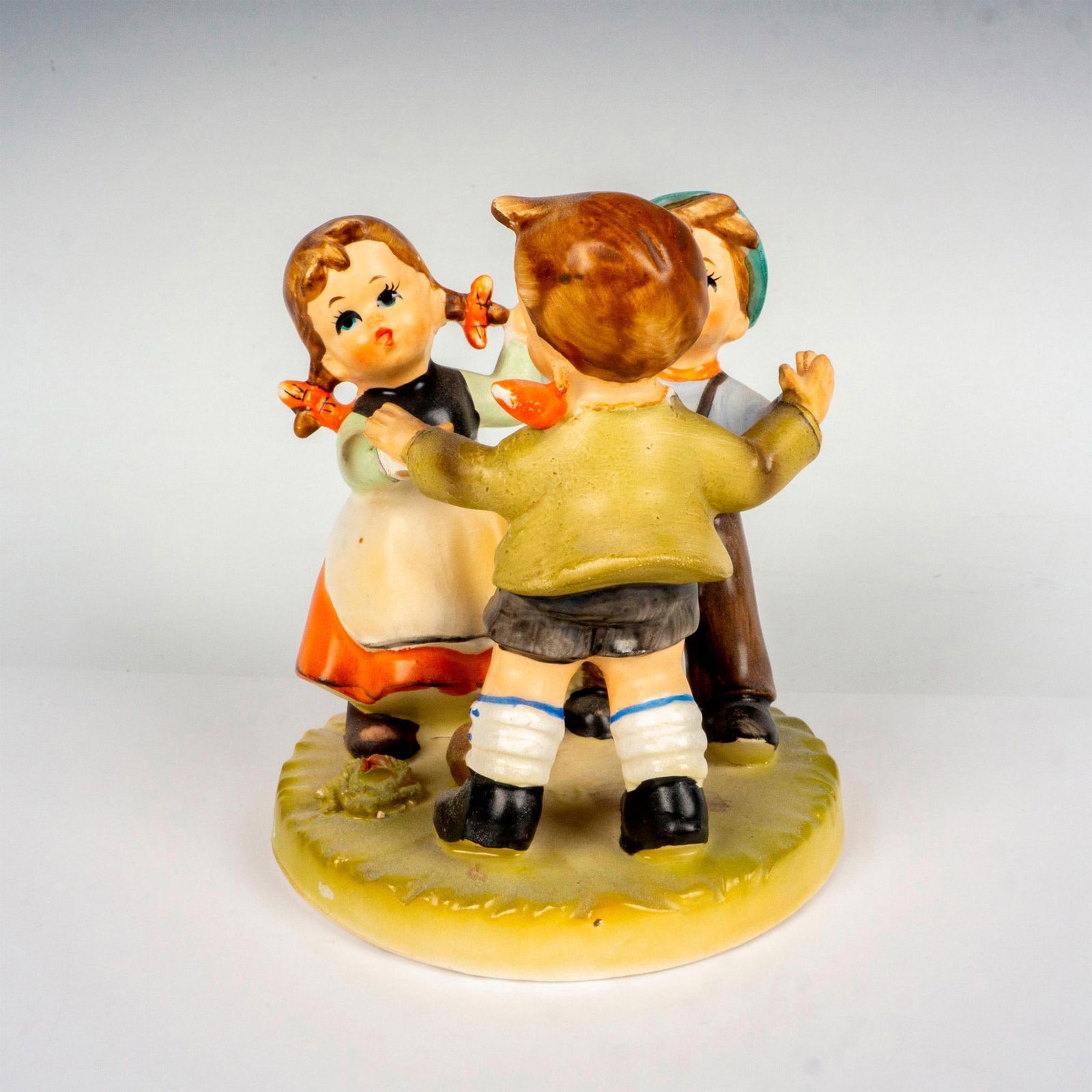 Erich Stauffer Porcelain Dancing Children Figurine: Hand painted in matte finish figure in the style of Goebel-Hummel. This charming figurine depicts three German children dancing and having a jolly time. Designed by Erich Stauffer backstamp. Artist: E
