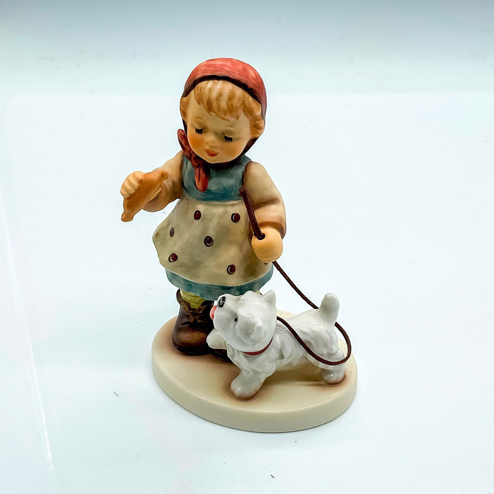 Goebel Hummel Porcelain Figurine, Christmas Treat: Holiday 2007 Special Edition, hand painted girl with dog on a leash. Goebel Germany backstamp. Impress mark 2264. Issued: 2007 Dimensions: 3"L x 2.25"W x 4"H Manufacturer: Goebel Hummel Country of Ori