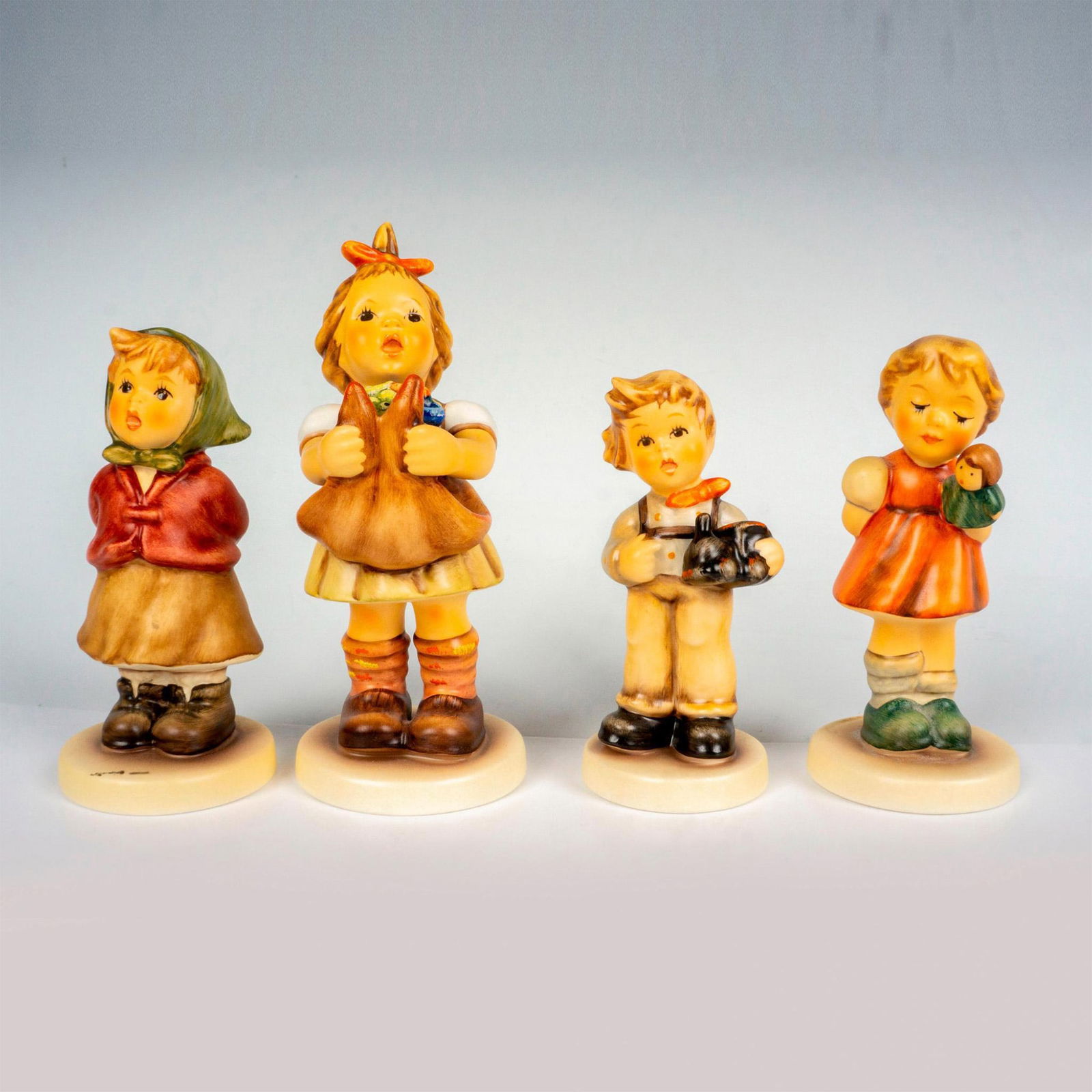 4pc Goebel Hummel Figurines: Hand painted in matte finish set that includes Puppet Princess, My Toy Train, Clear As a Bell, and Loving Wishes. Goebel backstamp. Tallest measures: 2"L x 2.5"W x 4.75"H. Shortest measures: 1.5"W x 3