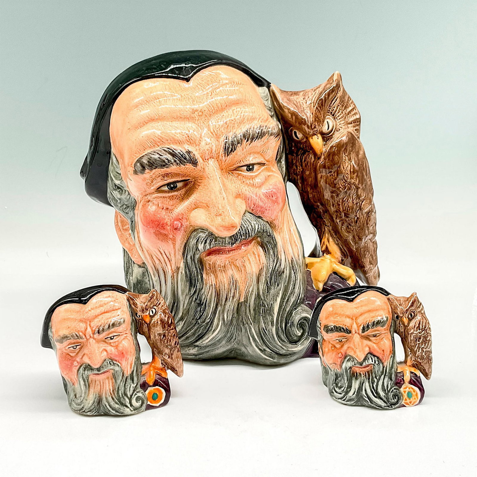 3pc Royal Doulton Porcelain Character Jugs, Merlin: Includes Large Merlin D6529 and 2 Mini D6543. Royal Doulton backstamp. Largest piece: 8"L x 6"W x 7.5"H. Artist: Gary Sharpe Issued: 1960 - 1998 Manufacturer: Royal Doulton Country of Origin: England