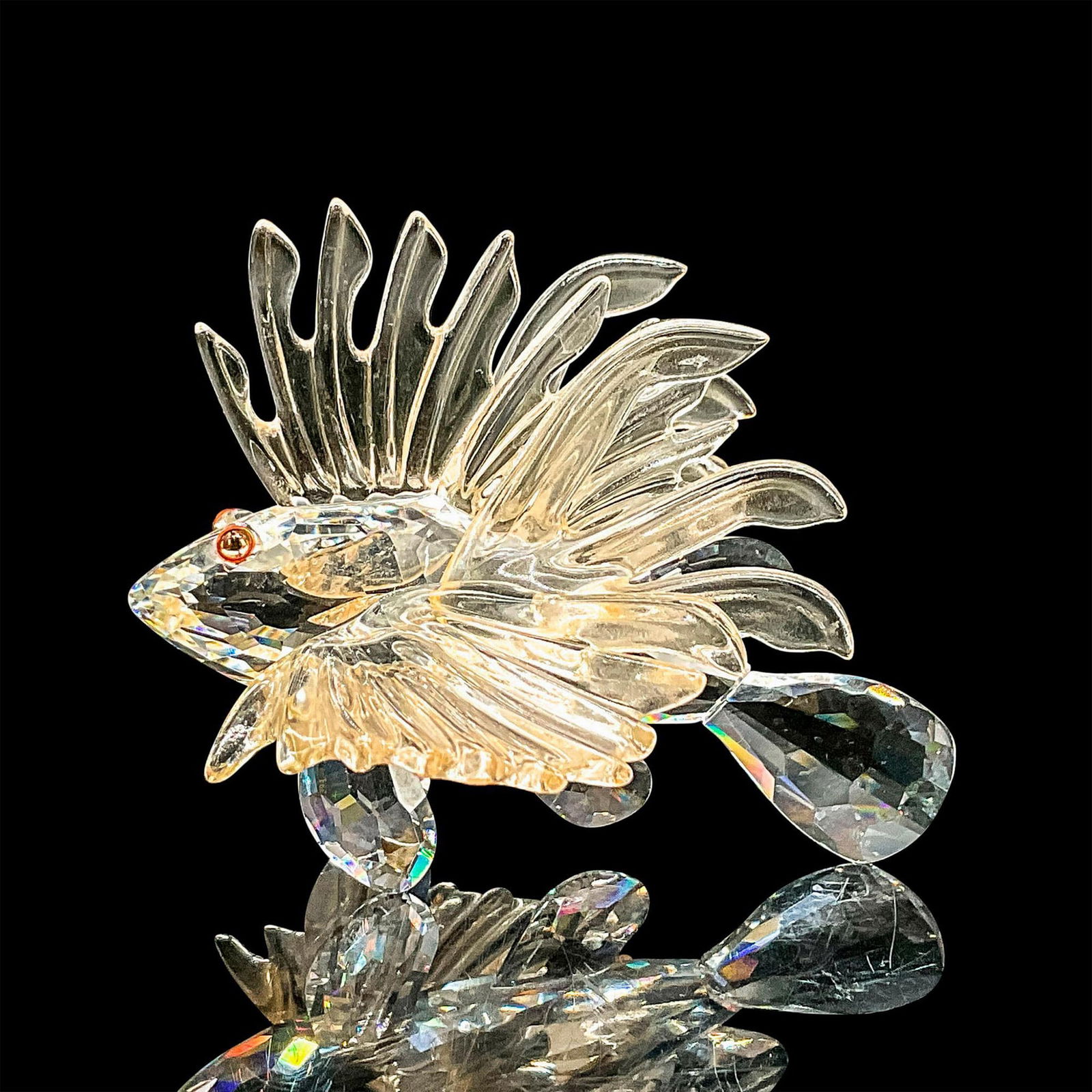 Swarovski Crystal Figurine, Lionfish: Clear faceted crystal figure of a lionfish with bright orange eyes. Fins are made of glass with a slight peach hue. Retired; part of the South Sea collection. Swarovski mark. Dimensions: 2.75"L x 2.75