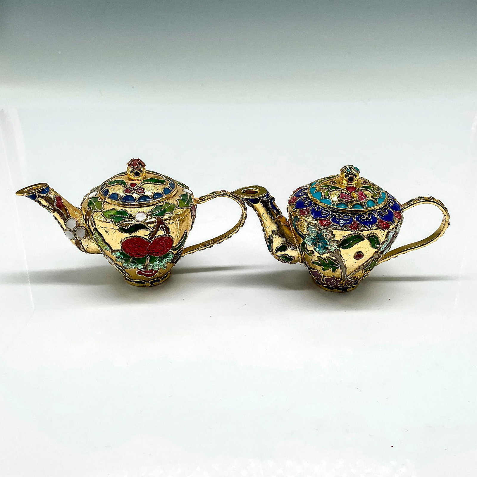 2pc Vintage Cloisonne Miniature Teapot Ornaments: Lovely, raised enamel over gold toned metal ornaments with floral designs colored in red, green, blue. Issued: 20th century Dimensions: 3"L