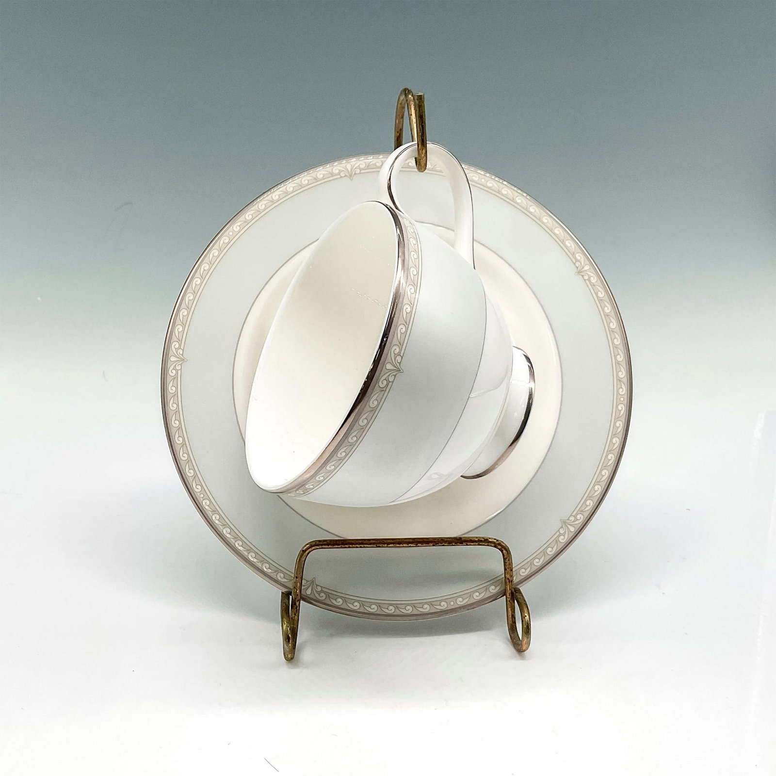 3pc Royal Doulton Bone China Teacup and Saucer, Anabel: Wave pattern over grey with silver toned accent on rim, handle and base. Included is hanger (3"L x 3.5"W x 7.25"H), cup (4.75"L x 3.75"W x 2.75"H) and saucer (0.50"H x 6.25" diameter). Royal Doulton b