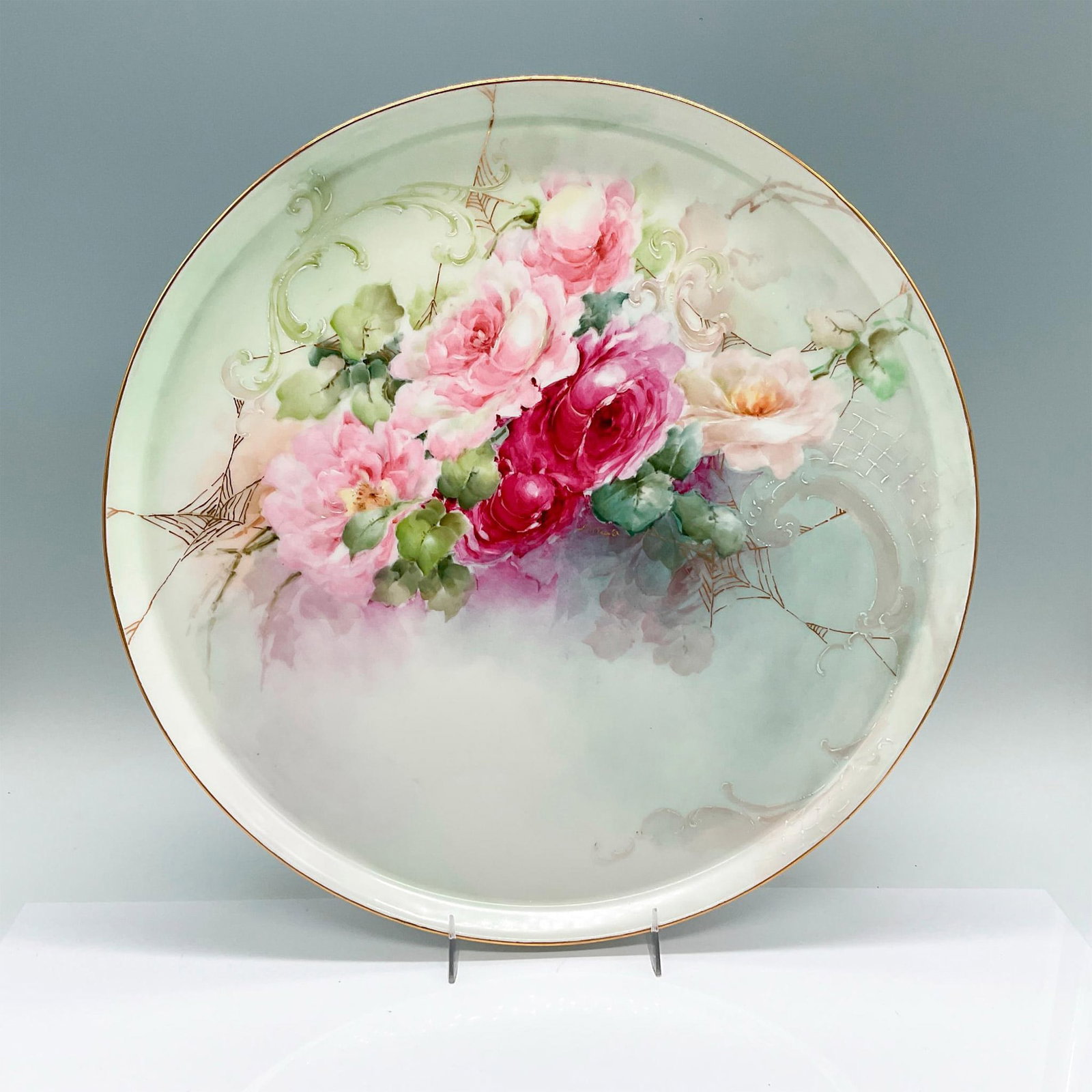 Tressemanes & Vogt M. Wright Porcelain Limoges Tray: A round tray with featuring hand painted pink and white roses, and gilded cobwebs. Tressemanes & Vogt marked. Artist signed on the front. Artist: M. Wright Issued: 1919-1928 Dimensions: 13.5"W x 0.75"