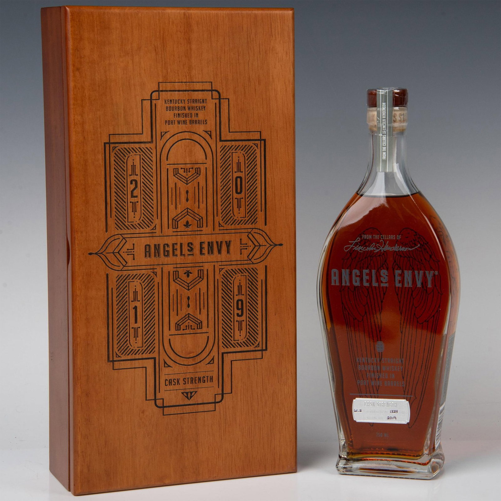 Angel's Envy Cask Strength Bourbon Port Barrel Finished: Angel's Envy Kentucky Straight Bourbon, finished in Ruby Port Wine barrels with batch number C8, is presented in a tapered glass bottle adorned with angel wings. Enclosed in a carved wooden chest, the