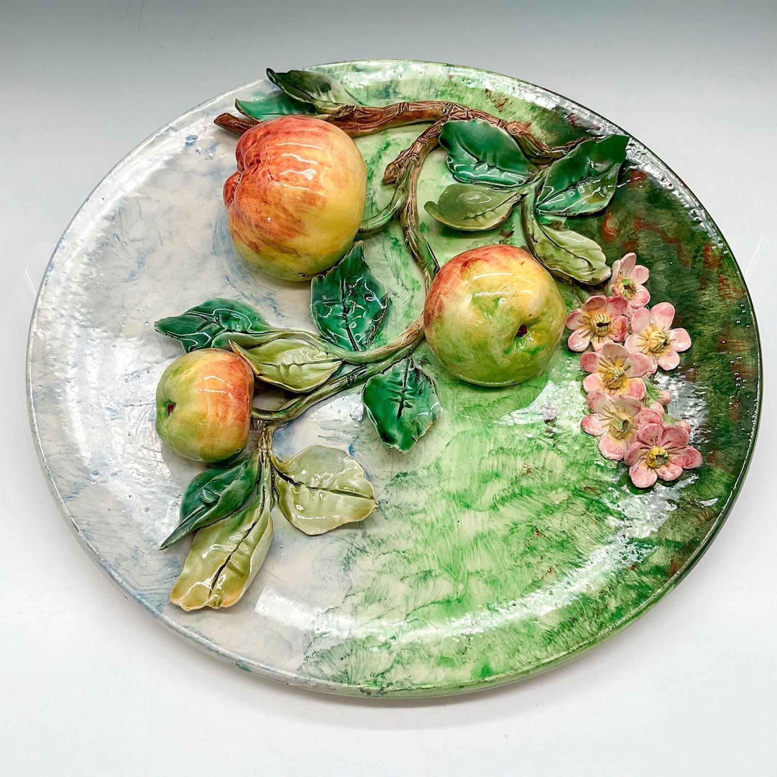 Longchamps Majolica Wall Platter with Applied Floral + Fruit: Glazed plate with applied fruit and floral design with branches and leaves. Colored in soft green and dappled blue. Longchamps impressed mark. Dimensions: 1"H x 14" dia. Manufacturer: Longchamps Count
