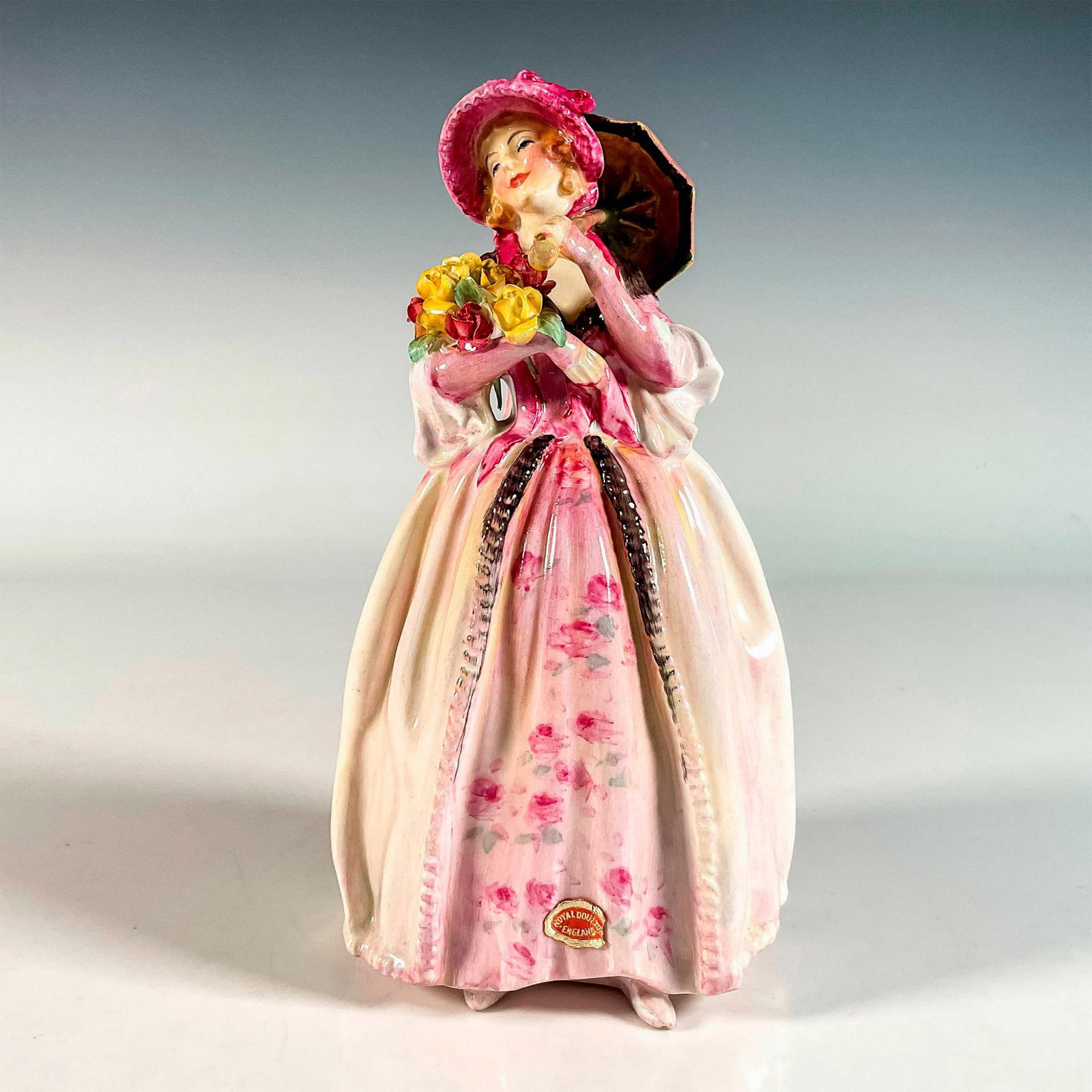 June HN1691 - Royal Doulton Figurine: She wears a gorgeous patterned gown, carrying pink and red roses. Handwritten HN number. Royal Doulton backstamp. Artist: Leslie Harradine Issued: 1935-1949 Dimensions: 3.75"L x 3.25"W x 7.5"H Manufac