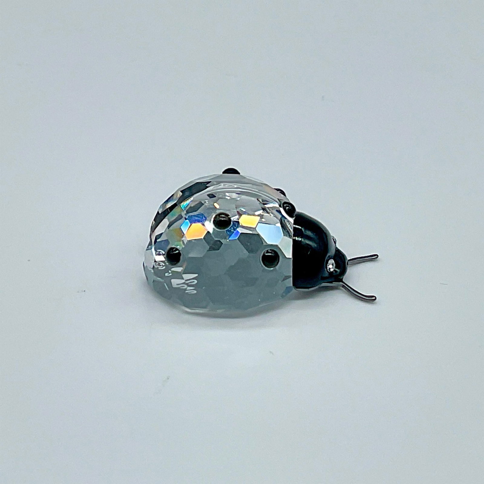 Swarovski Crystal Figurine, Ladybug: Clear body with black facets on back, black face with clear crystal eyes, metal antennae. Swarovski backstamp. This item has its original box which measures 2.5"H x 3.25" dia. Artist: Edith Mair Issue