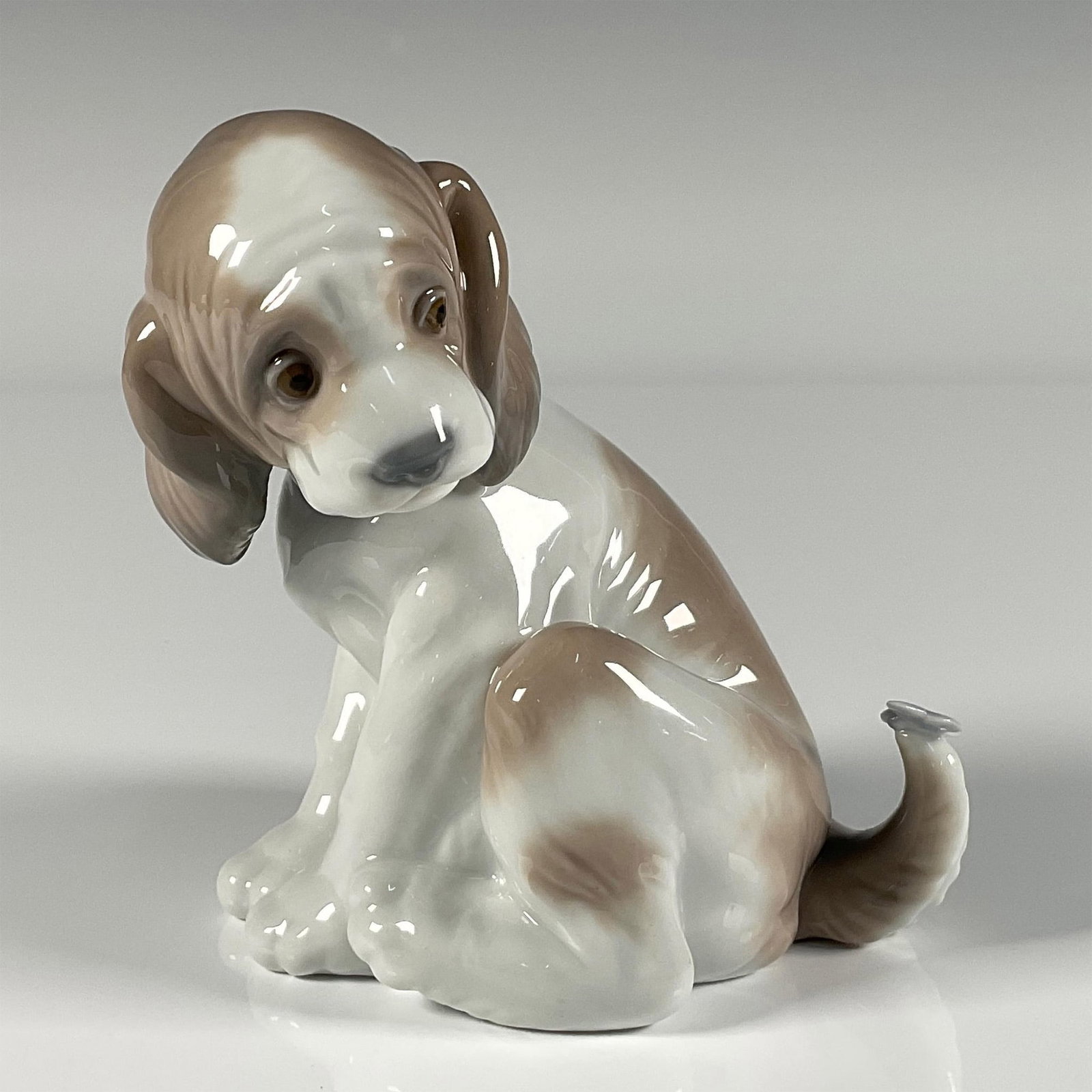 Gentle Surprise 1006210 - Lladro Porcelain Figurine: Glossy finish; adorable, spotted puppy with butterfly on tail. Lladro backstamp. This item has its original box. Box measures: 5.5"L x 8"W x 5"H. Artist: Juan Huerta Issued: 1995 Dimensions: 3.25"L x 