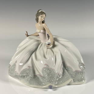 At the Ball 1005859 - Lladro Porcelain Figurine: Glossy finish; young elegant girl ready for the ball dance wearing a white dress with patten at the ends. Lladro backstamp. Artist: Jose Puche Issued: 1992 Dimensions: 8"L x 6.25"W x 6.5"H Manufacture