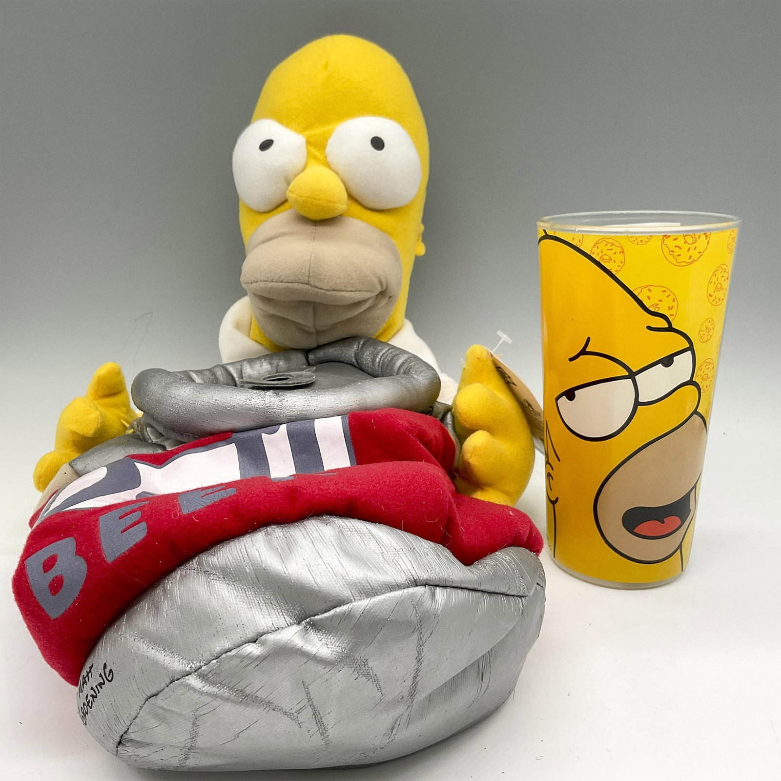 2pc Collectible The Simpsons, Homer Simpson Holiday Stocking + Glass: Includes soft, holiday stocking of Homer holding his Beer duffle. Colored in bright yellow and red. Plus glass with Homer's face and The Simpsons name on back. Kurt S. Adler tag. Largest piece: 9.5"L 