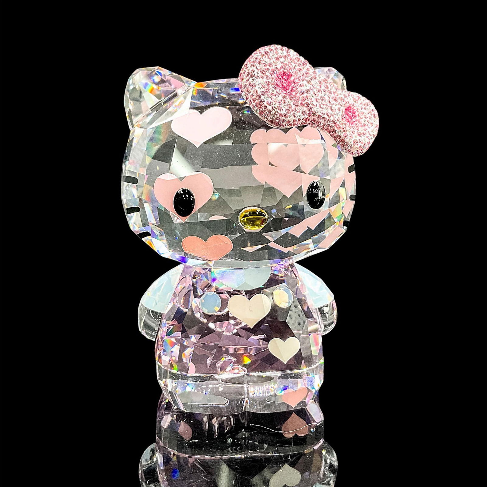 Swarovski Crystal Figurine, Hello Kitty: Fun faceted crystal figure of Hello Kitty with a pink bow encrusted with pink and clear crystals. Swarovski mark. Item number 1142934. This item has its original box: 6.75"L x 6.75"W x 4.75"H. Certifi