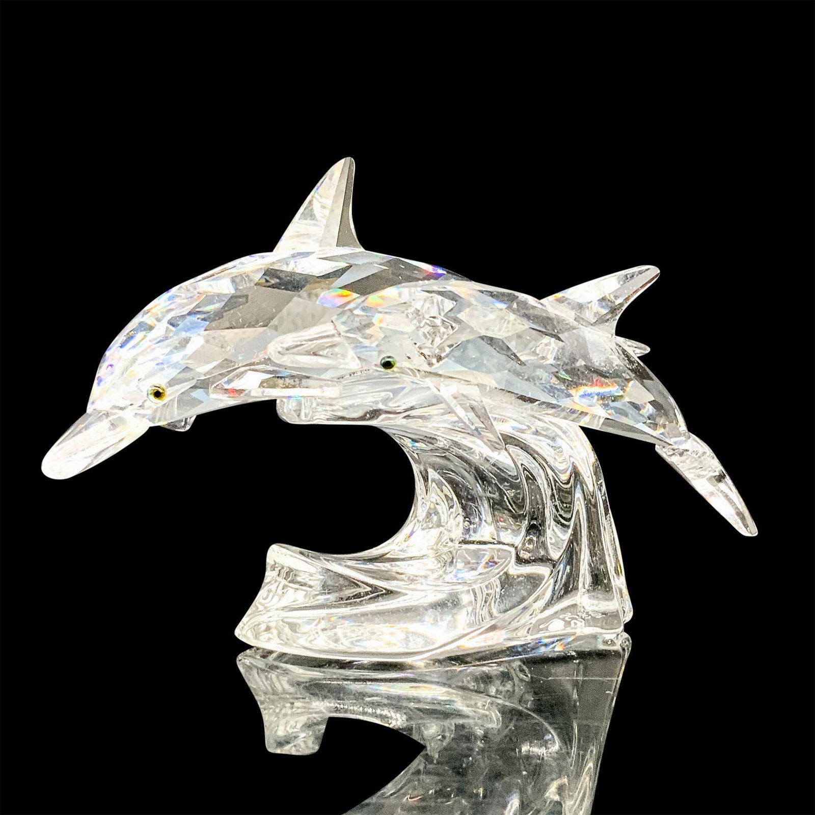 Swarovski Crystal Figurine, Lead Me 153850: A clear crystal figure depicting a mother and child dolphin swimming side by side over a wave. Melon colored crystals are used for the eyes. Swarovski backstamp. This item has its original box. Dimens