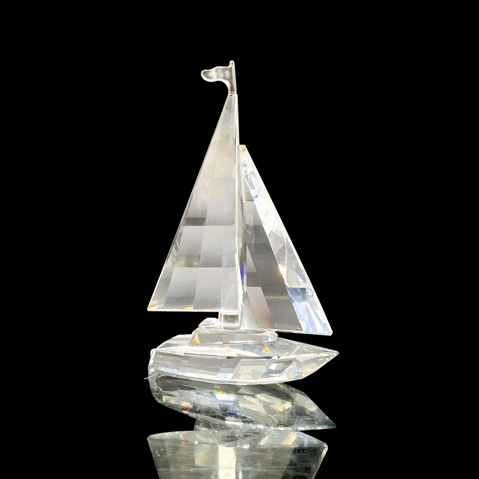 Swarovski Crystal Figurine, Sailboat 183269: A clear crystal figure of a sailboat with an open mast with a flag at the top. Swarovski backstamp. This item has its original box. Dimensions of the original box: 4.75"H x 6" dia. Artist: Gabriele St