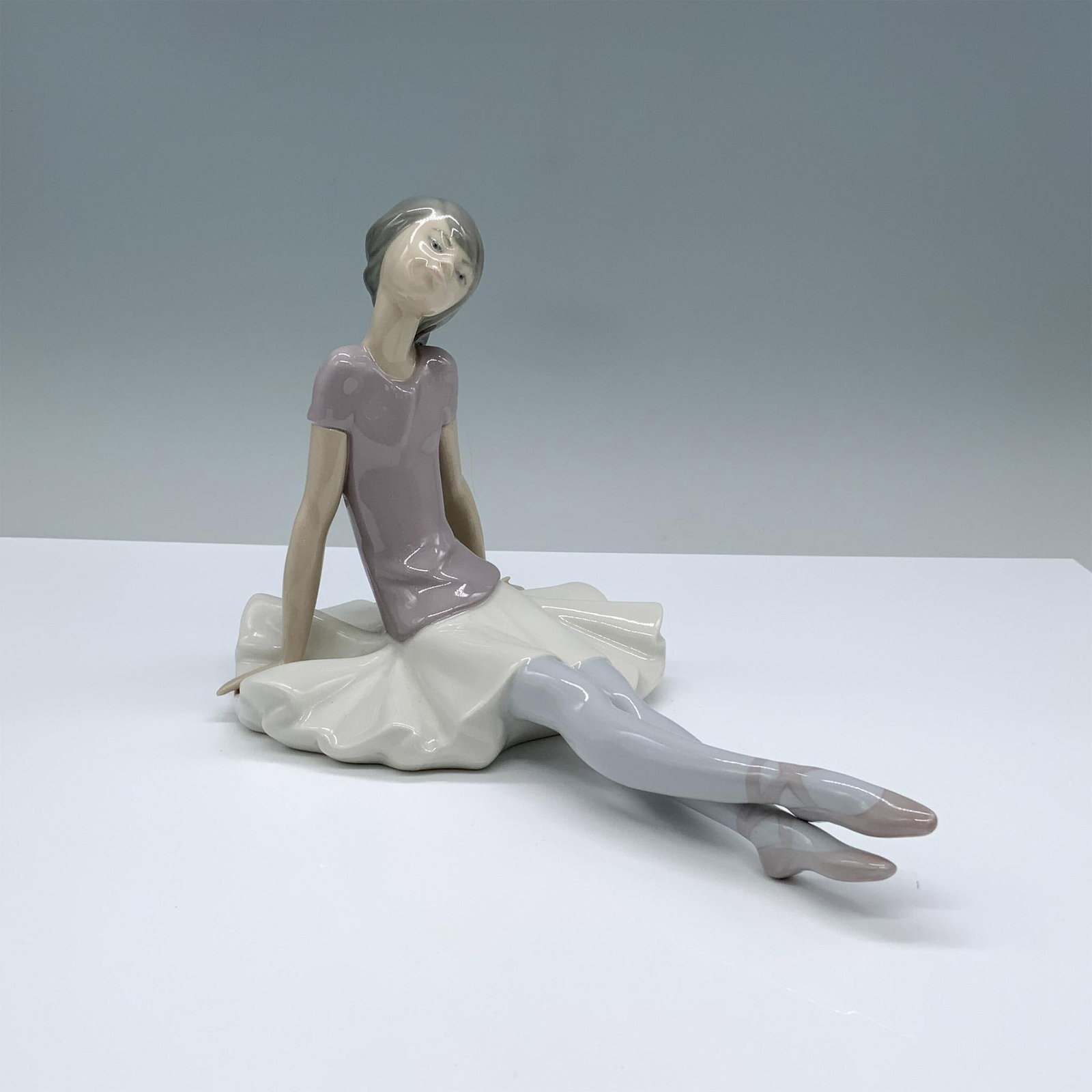 Phyllis 1001356 - Lladro Porcelain Figurine: Sitting ballerina in glossy finish. Lladro backstamp. Artist: Juan Huerta Issued: 1978 Dimensions: 9.75"L x 5.25"W x 6"H Manufacturer: Lladro Country of Origin: Spain
