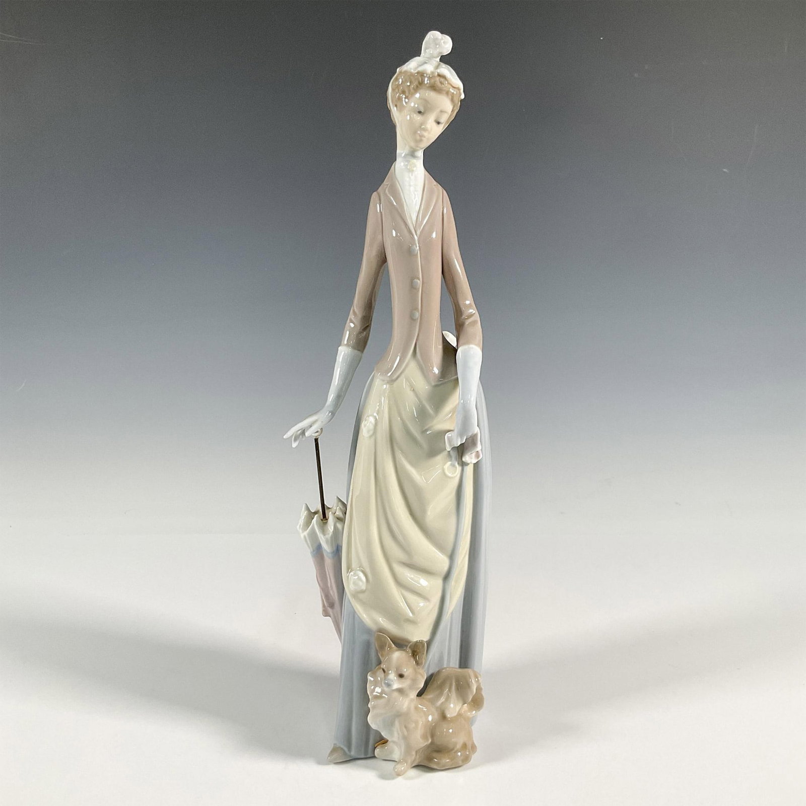 Woman with Dog 1004761 - Lladro Porcelain Figurine: A glossy figure of a young woman with her dog and parasol. Lladro backstamp. Artist: Vincente Martinez Issued: 1971-1993 Dimensions: 4.5"L x 4.5"W x 14"H Manufacturer: Lladro Country of Origin: S