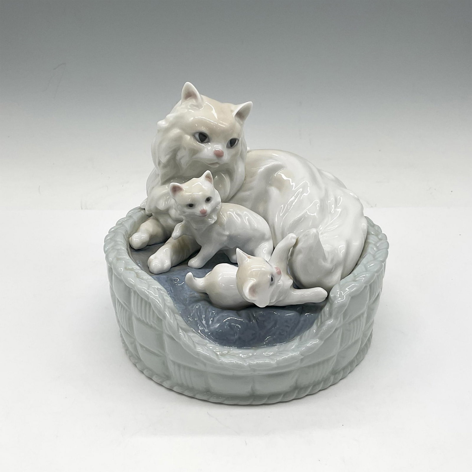 Kitty Care 1006652 - Lladro Porcelain Figurine: Glazed figural of mother cat with her kittens. Colored in cream, white and blue. Lladro backstamp. Artist: Jose Luis Alvarez Issued: 2000 - 2002 Dimensions: 4.5"H x 5.5"W Manufacturer: Lladro Country