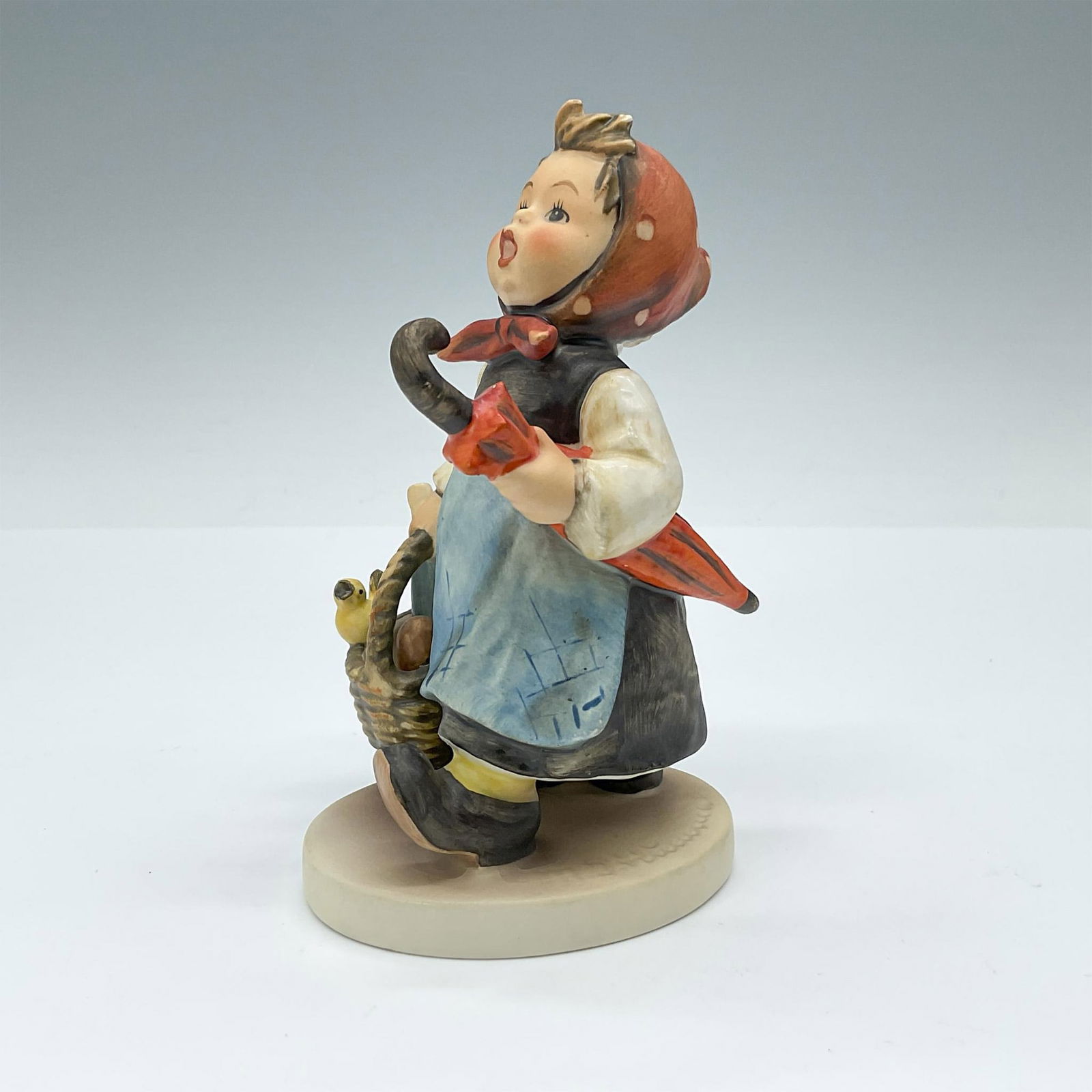 Visiting an Invalid - Goebel Hummel Figurine: Porcelain figurine depicting your girl with a picnic basket going to visit someone. Goebel TMK5. Issued: 1972-1979 Dimensions: 3"L x 3.25"W x 5"H Manufacturer: Goebel Hummel Country of Origin: Germany