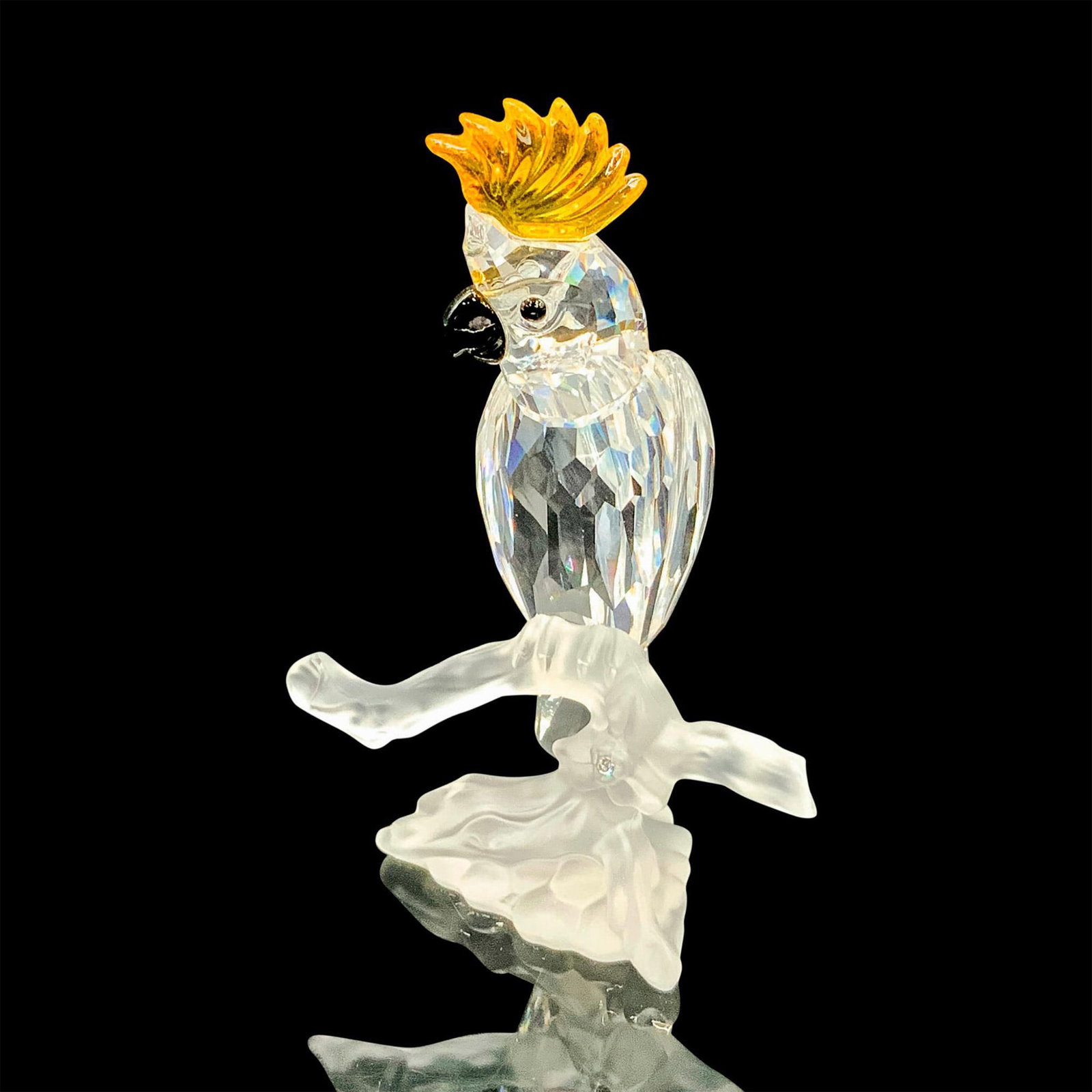 Swarovski Crystal Figurine, Cockatoo 261635: This retired Cockatoo bird has a clear crystal facetted body, a black beak and a yellow crest. It is sitting on a frosted crystal branch. Swarovski acid stamp on tail. The box measures 3.25"dia. x 6"H