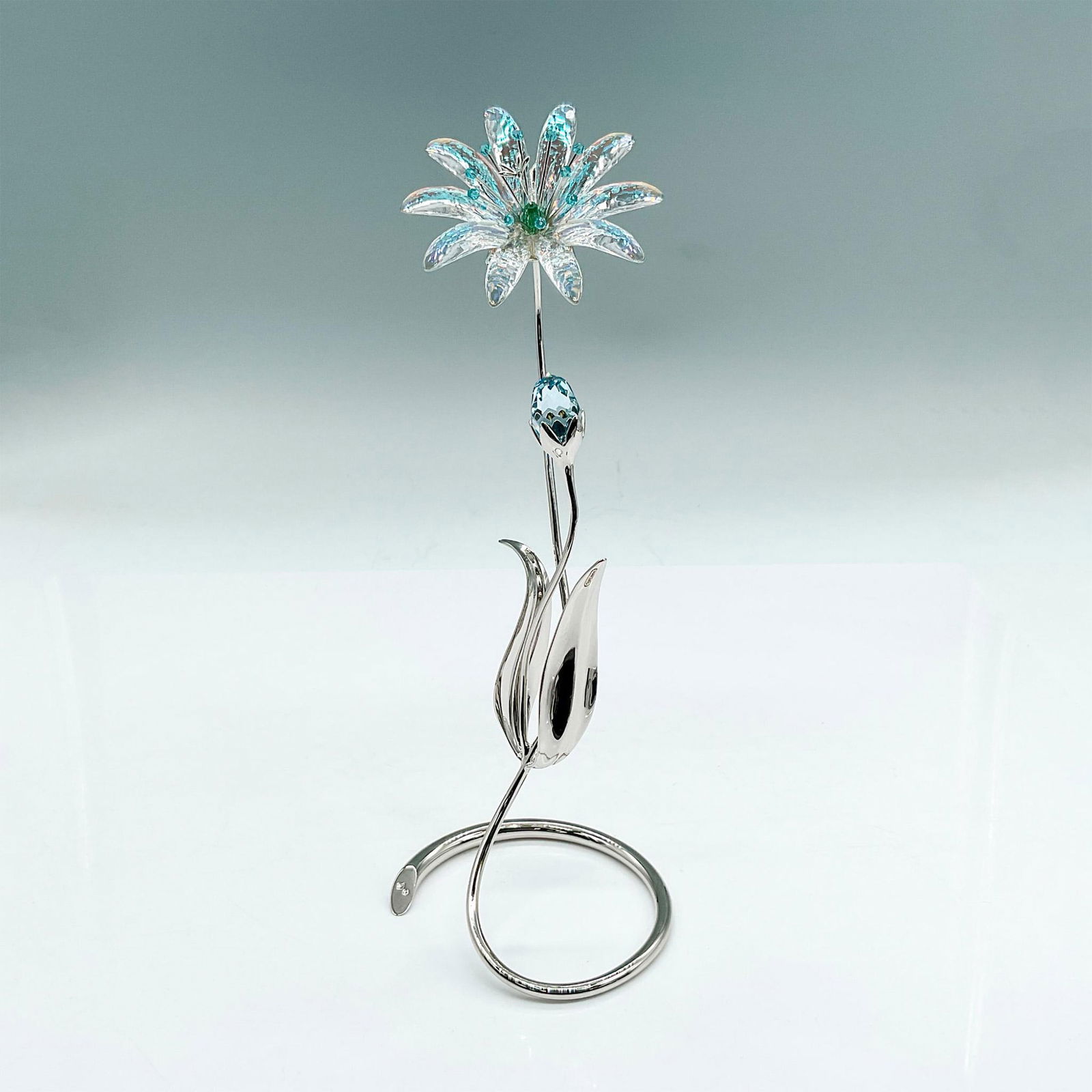 Swarovski Crystal Figurine, Dellaria Flowers: Soft blue Aurora Borealis crystal flower that refracts light, changing Colour at different angles. Light blue bud, rhodium-plated metal stems and leaves. Swarovski backstamp. Includes original box: 12