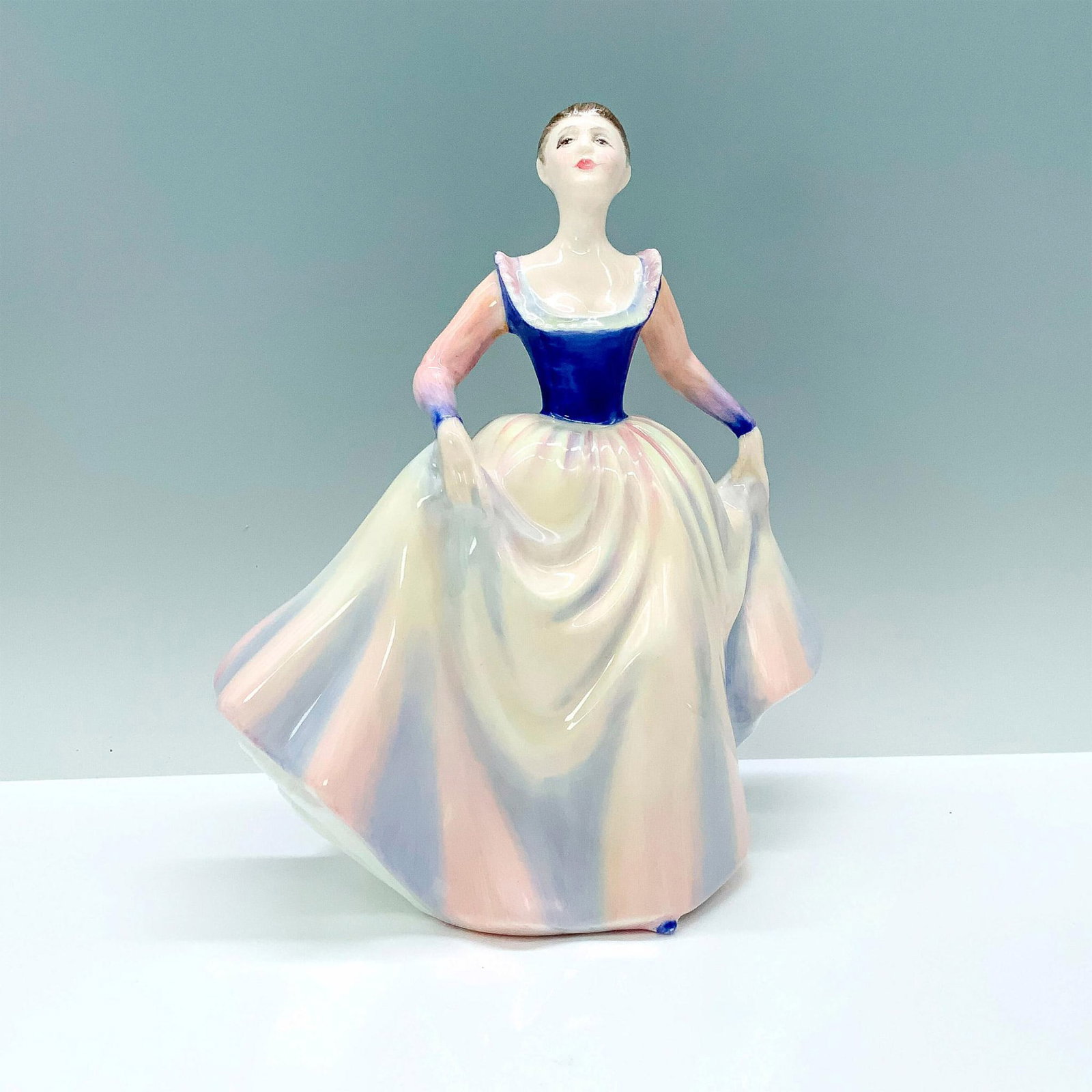 Lisa HN2394 - Royal Doulton Figurine: A woman modeled in a white, pink, and lavender dress. Glossy finish. Bone China. Royal Doulton backstamp. Artist: Peggy Davies Issued: 1983 - 1990 Dimensions: 7.25"H Manufacturer: Royal Doulton Count