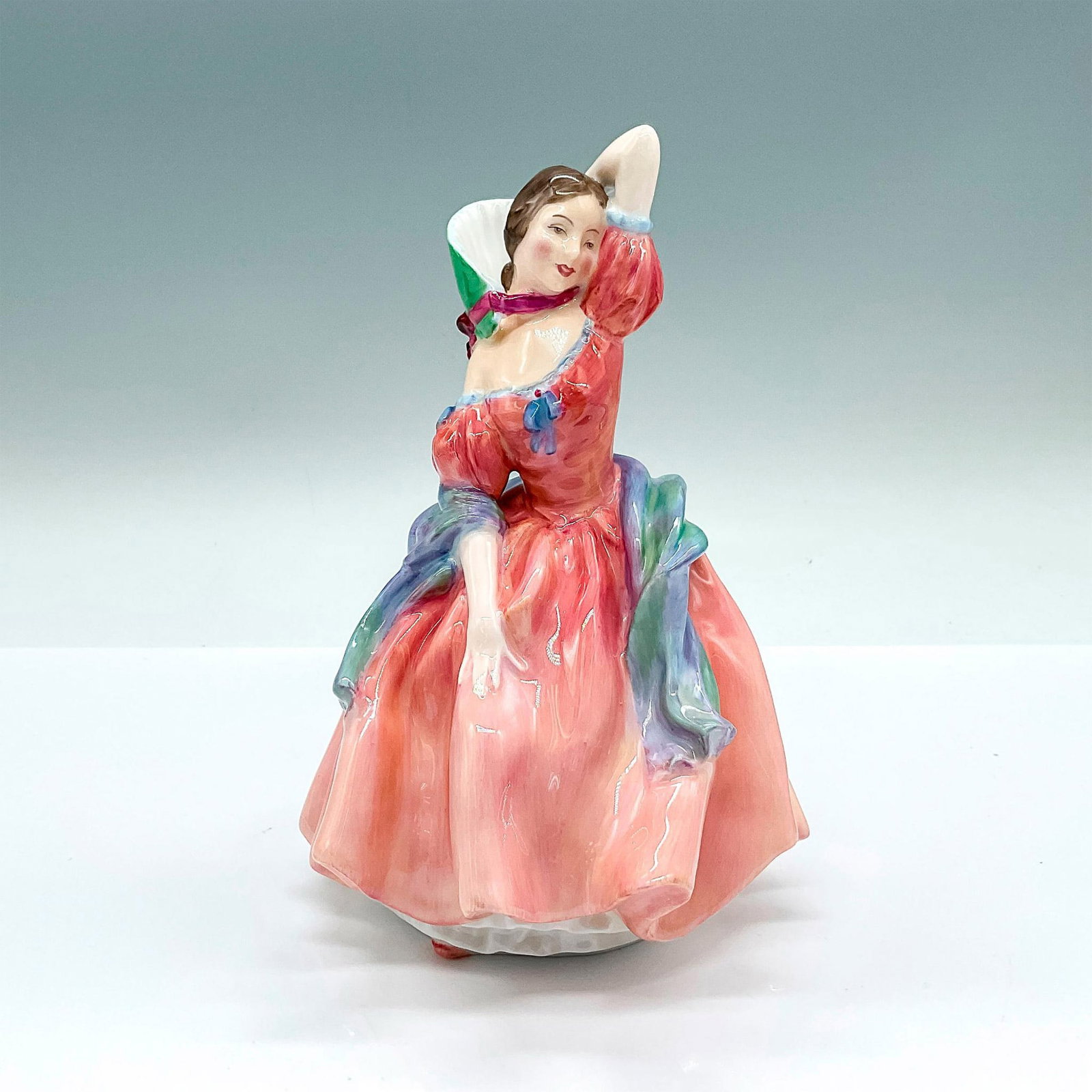 Maytime HN2113 - Royal Doulton Bone China Figurine: Glazed figure of a young lady in a pink dress with a green and blue scarf. Royal Doulton backstamp. Artist: Leslie Harradine Issued: c. 1953-1967 Dimensions: 5"L x 5"W x 7"H Manufacturer: Royal Doulto