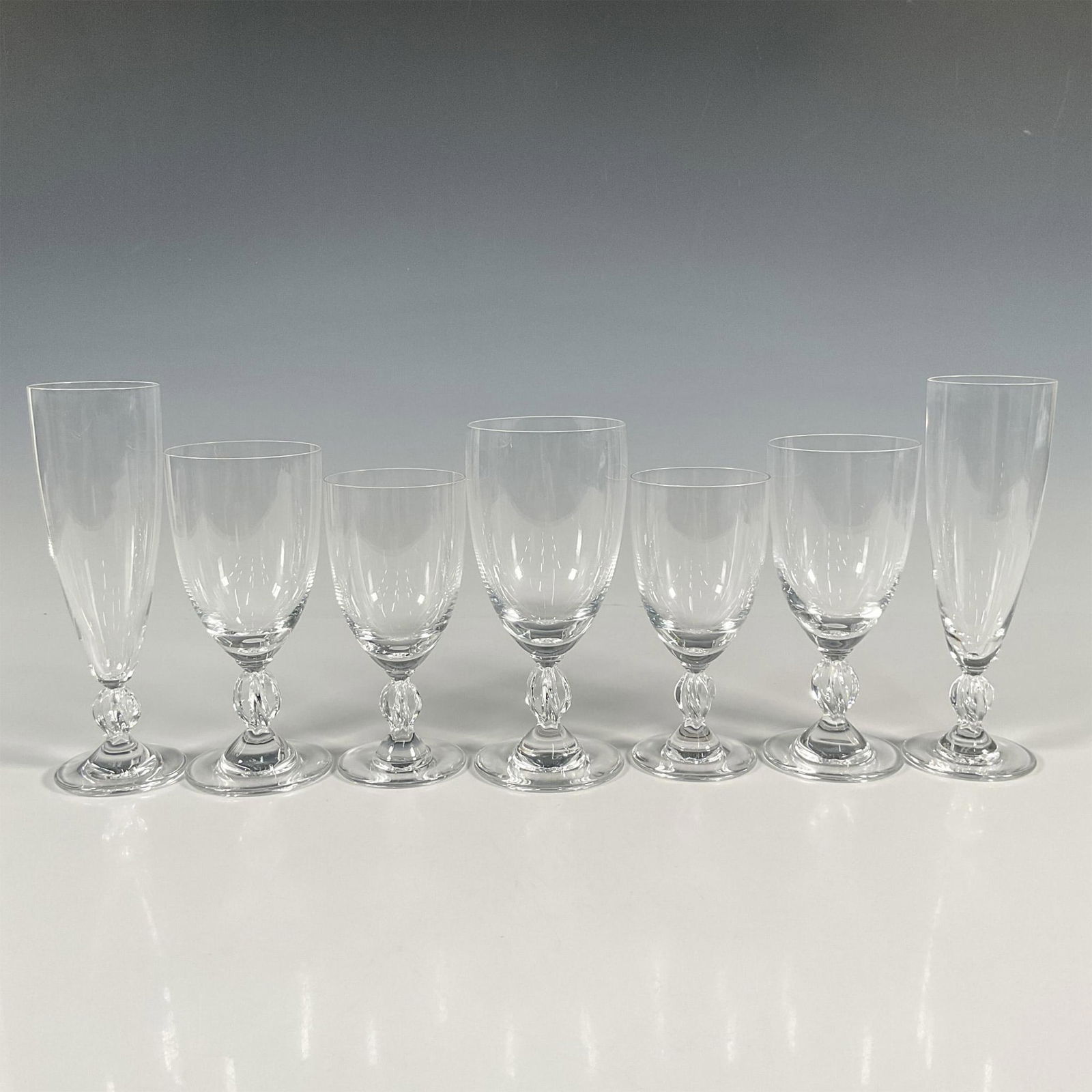 7pc Assorted Lalique Crystal Glasses, Frejus: Collection of seven various crystal glasses comprising of 1 Water Goblet, 2 Fluted Champagne Glasses, 2 Bordeaux Wine Glasses, and 2 Burgundy Wine Glasses. All delicately adorned with a twisted stem f