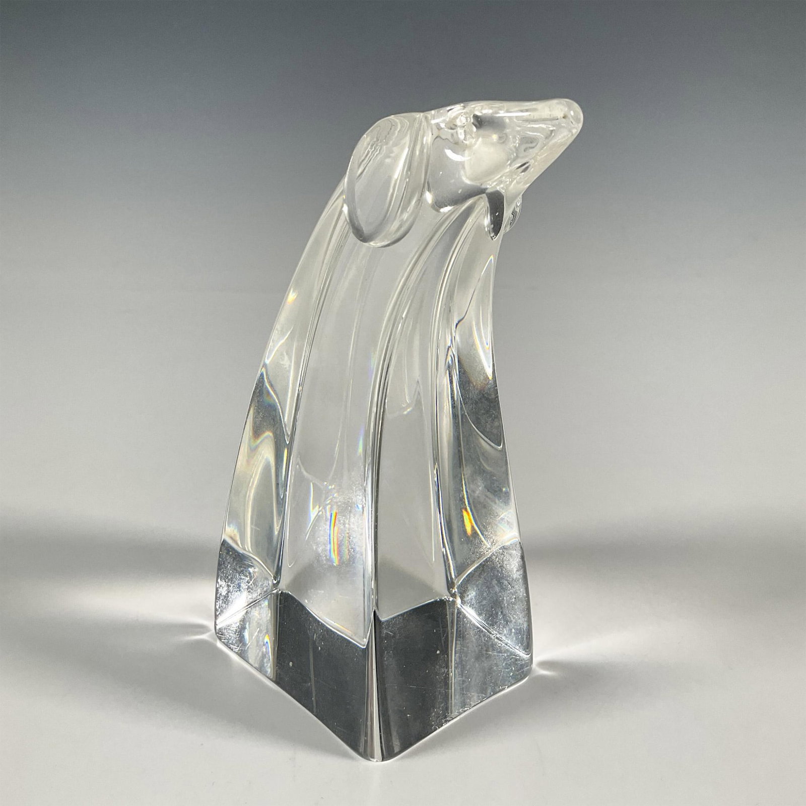 Steuben Art Glass Dog Paperweight: A vintage glass paperweight with rectangular body and the head of a dog. Steuben etched backstamp. Dimensions: 2.25"L x 3.25"W x 5.75"H Manufacturer: Steuben Country of Origin: United States