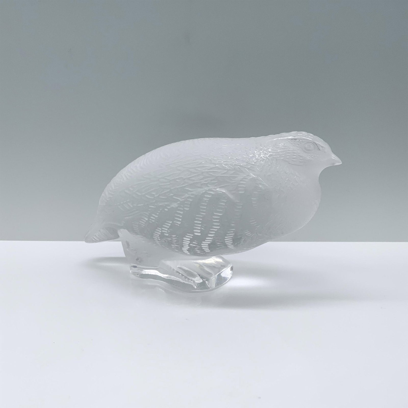 Lalique Crystal Figurine, Perdrix Couchee: A crystal figurine depicts a partridge crouched low, exuding an air of cautious vigilance in its delicate form. Signed Lalique France. Dimensions: 6"L x 3.25"W x 3.5"H Manufacturer: Lalique Country of