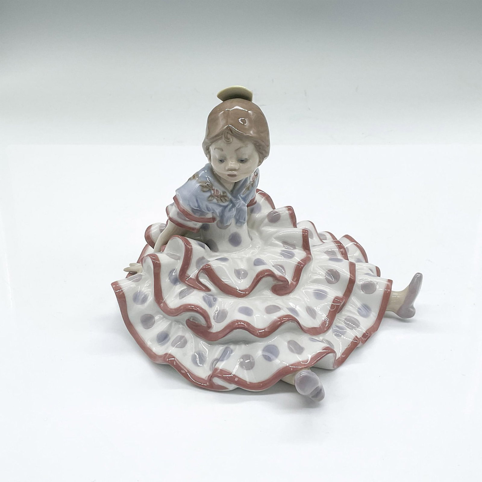 Lladro Porcelain Figurine, A Time To Rest: A young girl in a polka dot dress leaning back while sitting on the floor. Gloss finish. Lladro backstamp. Issued: 20th century Dimensions: 5.75"L x 6"W x 4.75"H Manufacturer: Lladro Country of Origin