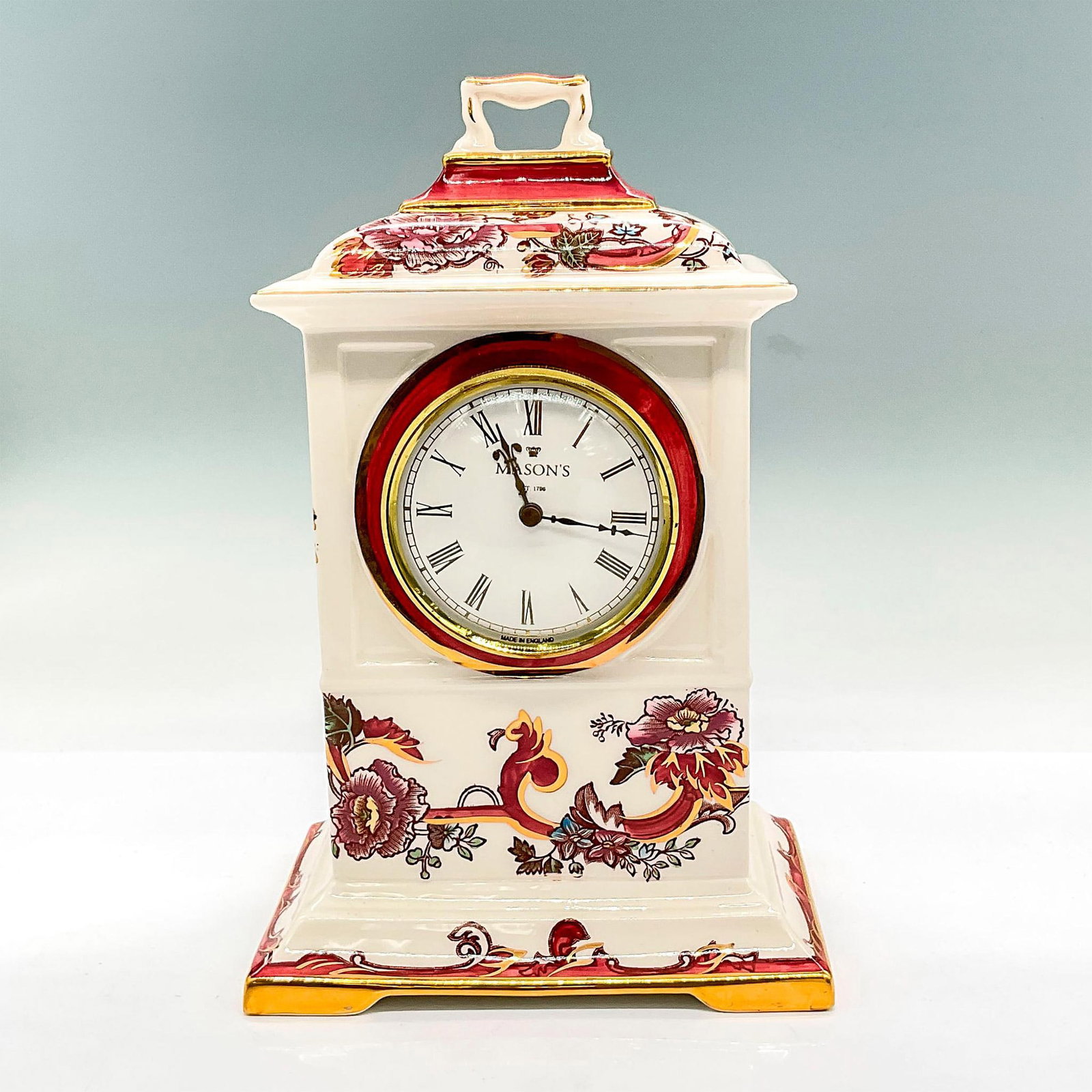 Mason's Ironstone Mantle Clock, Flowers: Off-white hand painted clock with mauve, lilac and gold floral design. Removeable clock which requires an E90 battery (not included). Mason's backstamp. Dimensions: 6"L x 4"W x 9.5"H Manufacturer: Mas