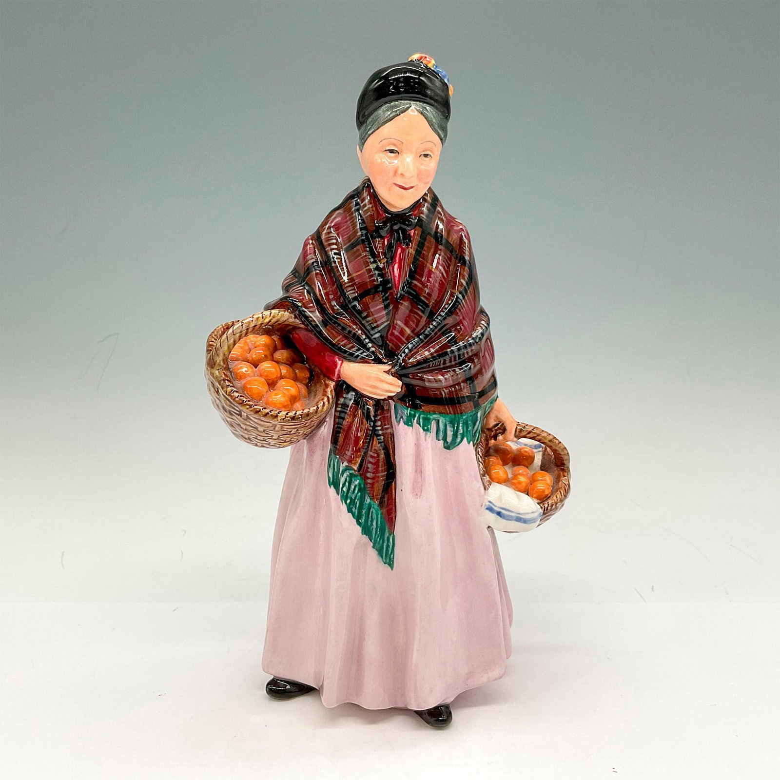 The Orange Lady - HN1759 - Royal Doulton Porcelain Figurine: Figural dressed in shawl and hat carrying baskets of oranges. Royal Doulton backstamp. Artist: Leslie Harradine Issued: 1936 - 1975 Dimensions: 5"L x 3.25"W x 8.75"H Manufacturer: Royal Doulton Count